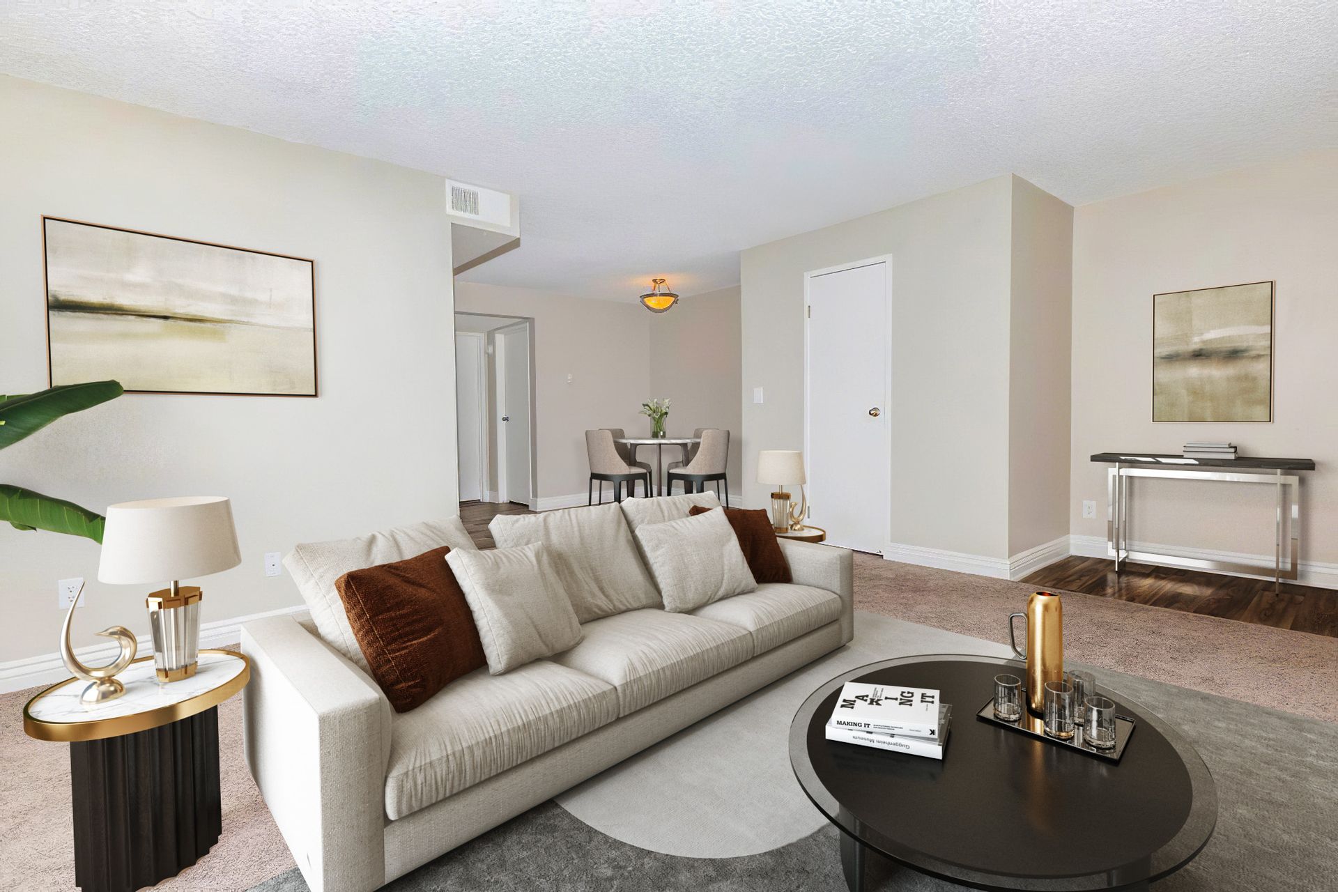 Living room with couch, coffee table, and art; open to dining area.