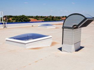 Rooftop with two skylights and a vent under a clear sky