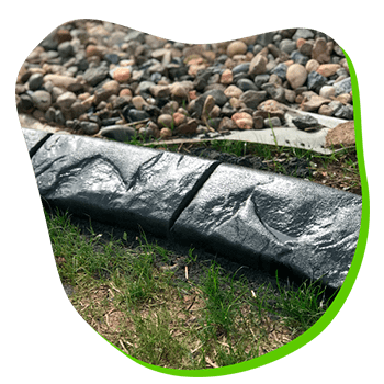 A concrete curb is sitting in the grass next to a pile of rocks.