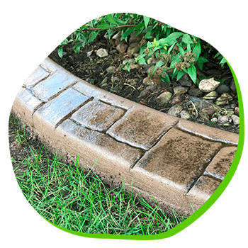 A concrete curb is surrounded by grass and rocks in a garden.