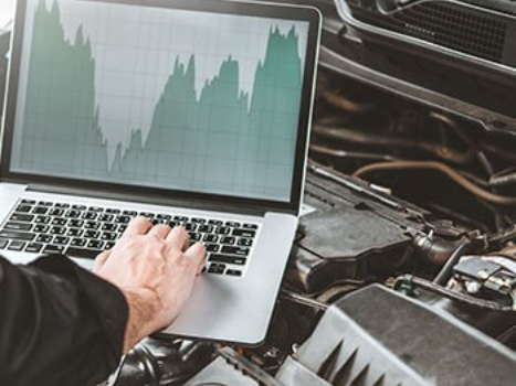 A mechanic using a laptop connected to a car for diagnostics