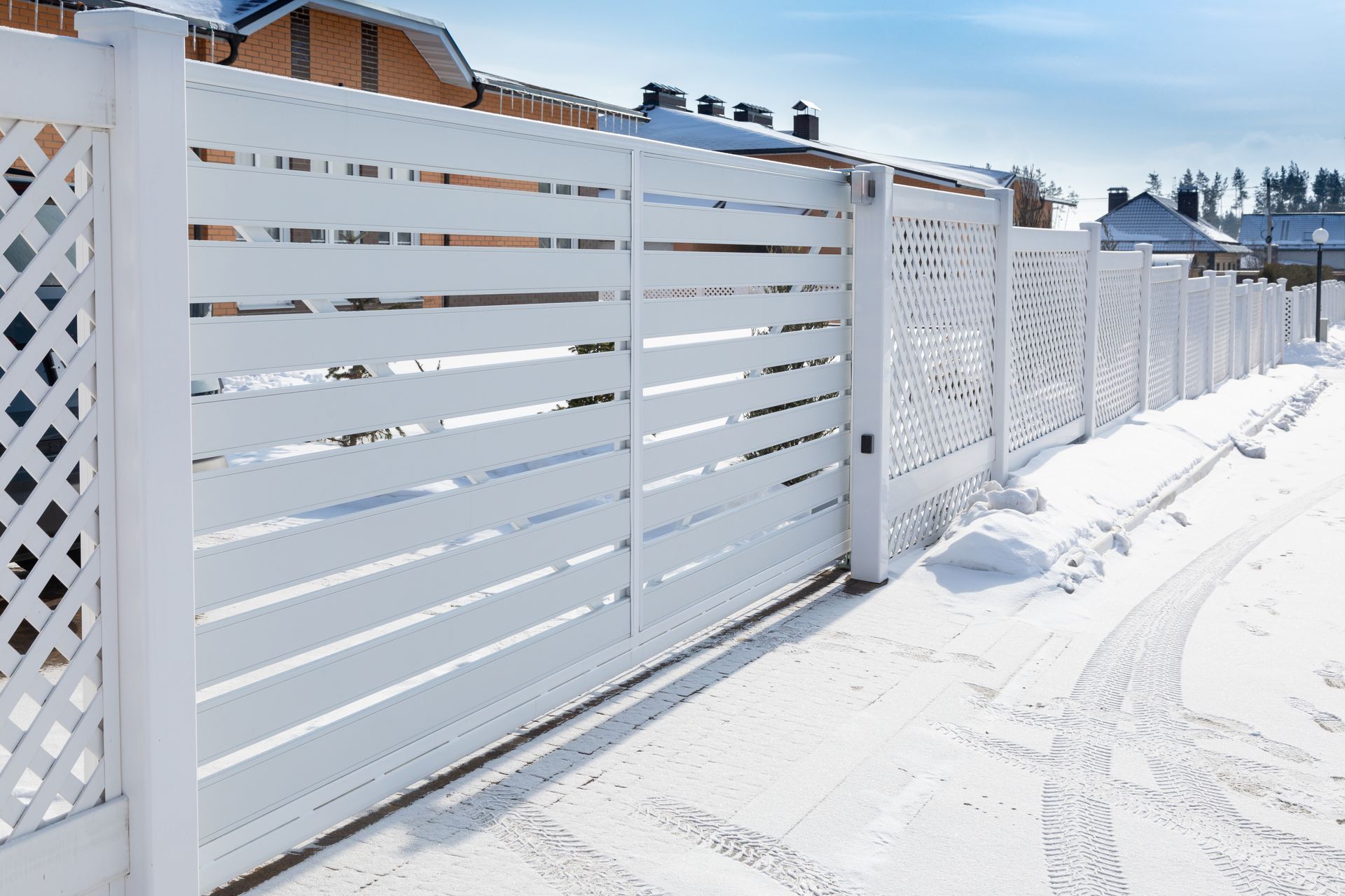 White horizontal-slat fence with a lattice section in a snowy environment. White horizontal-slat fence with a lattice section in a snowy environment.