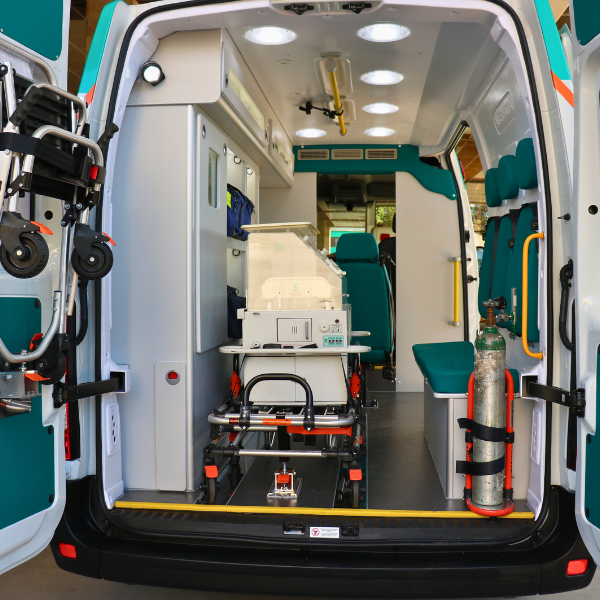 Interior de uma ambulância, mostrando uma maca, equipamentos médicos e luzes de teto.