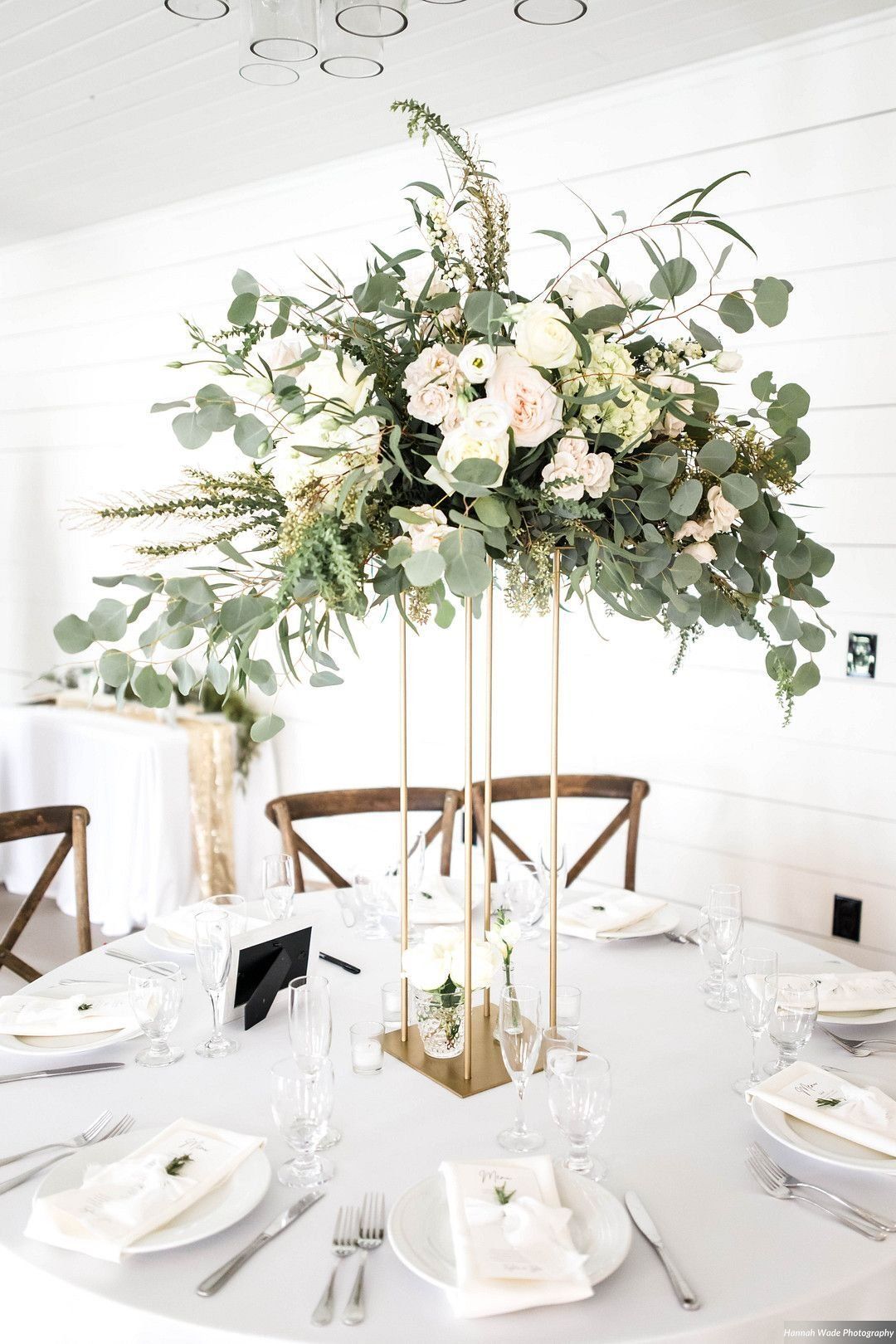 Elegant white-and-gold banquet table with a tall greenery and white floral centerpiece