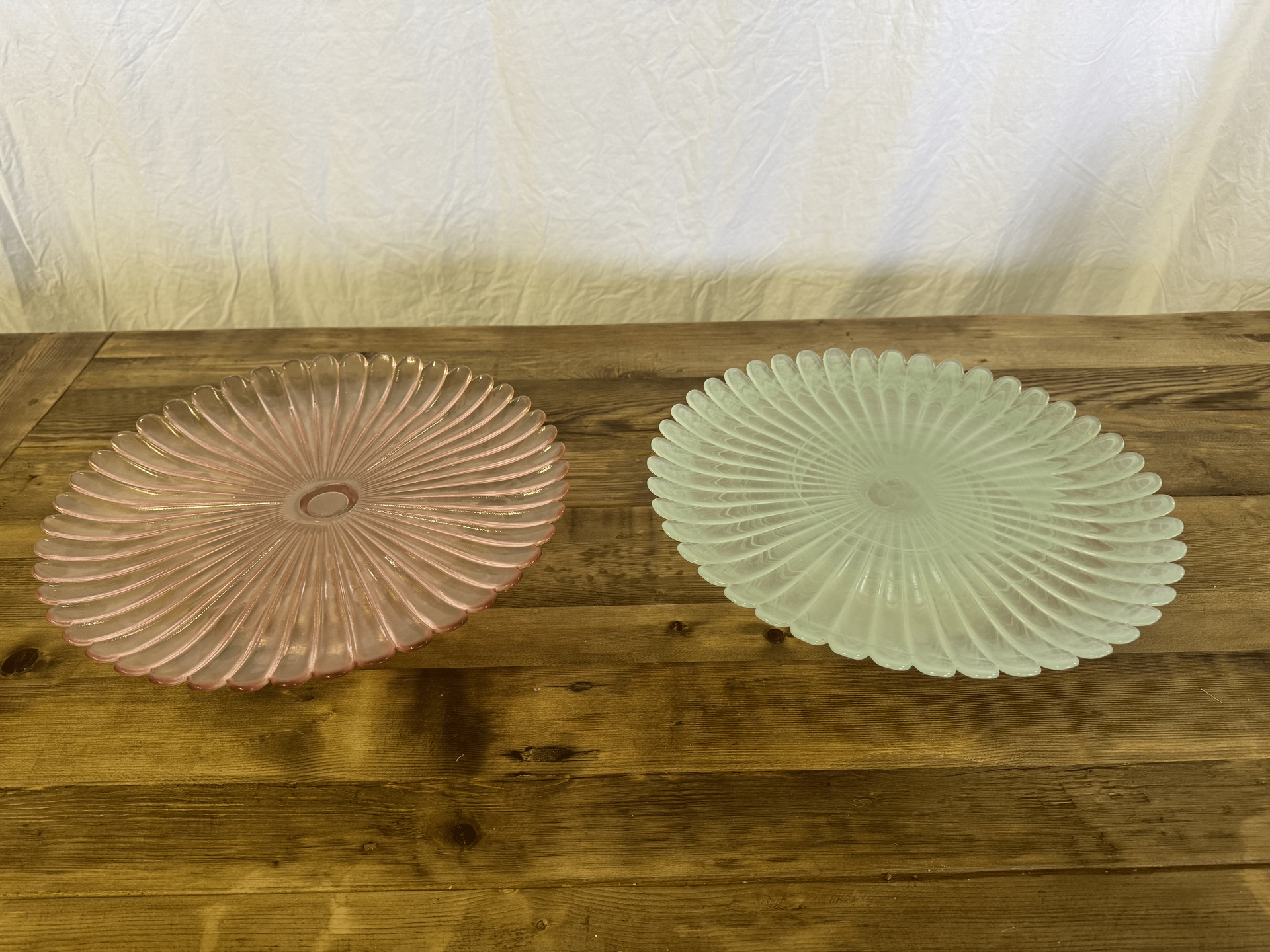 Two decorative glass plates, one pink and one pale green, on a wooden surface.