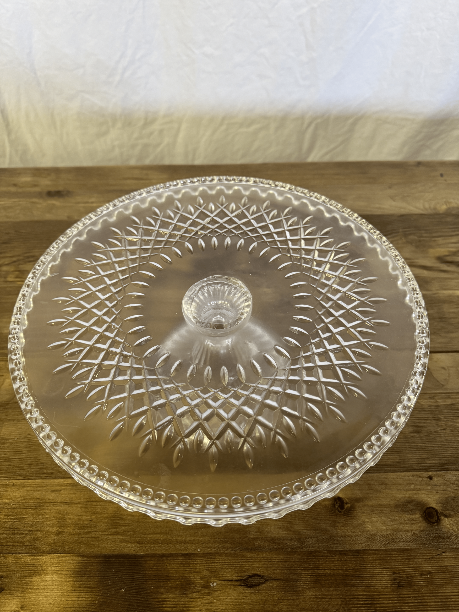 Clear glass lidded serving dish with a diamond-patterned design on a wooden table