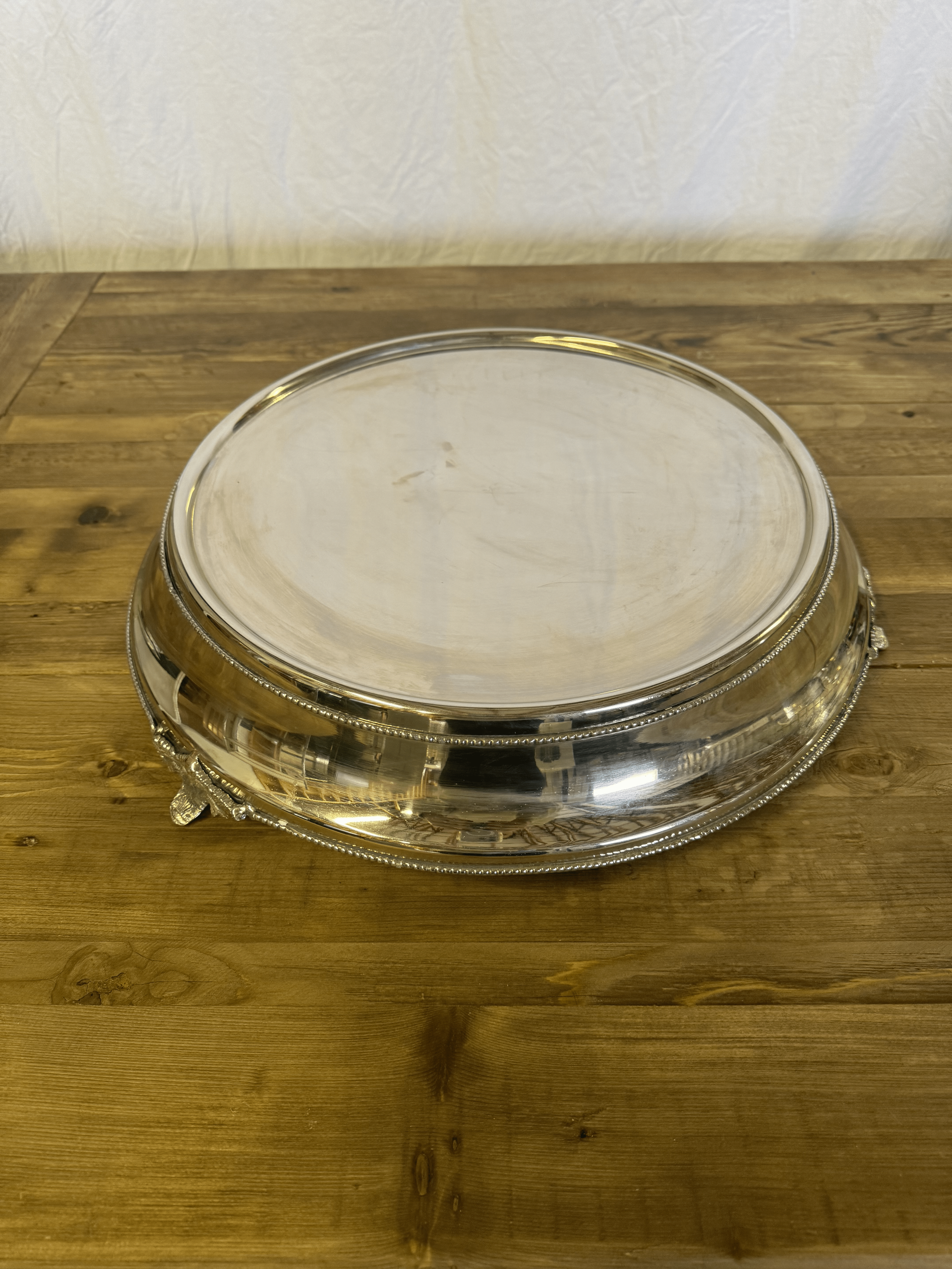 Clear plastic dessert dome on a wooden table against a plain wall