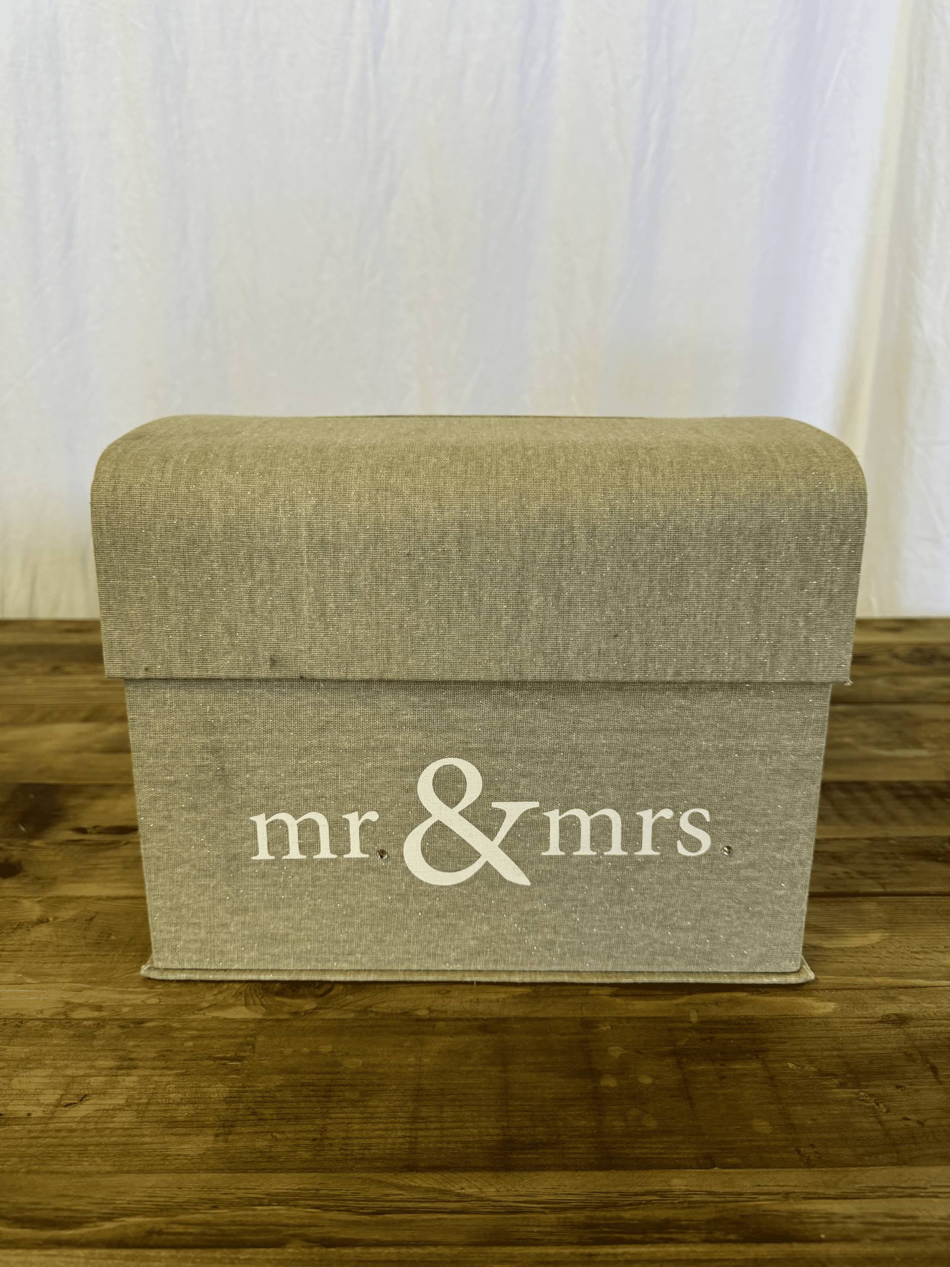Beige woven storage box with “mr & mrs.” text on a wooden floor against a white backdrop