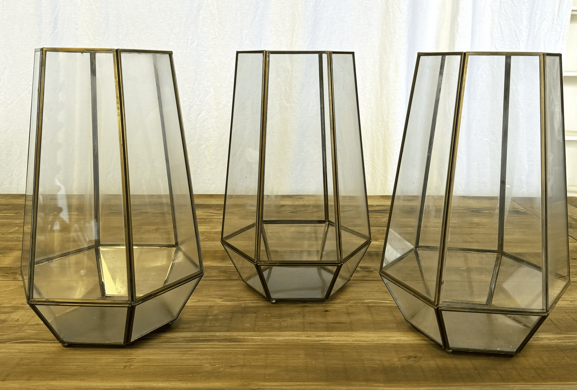 Three gold geometric glass vases on a wooden surface