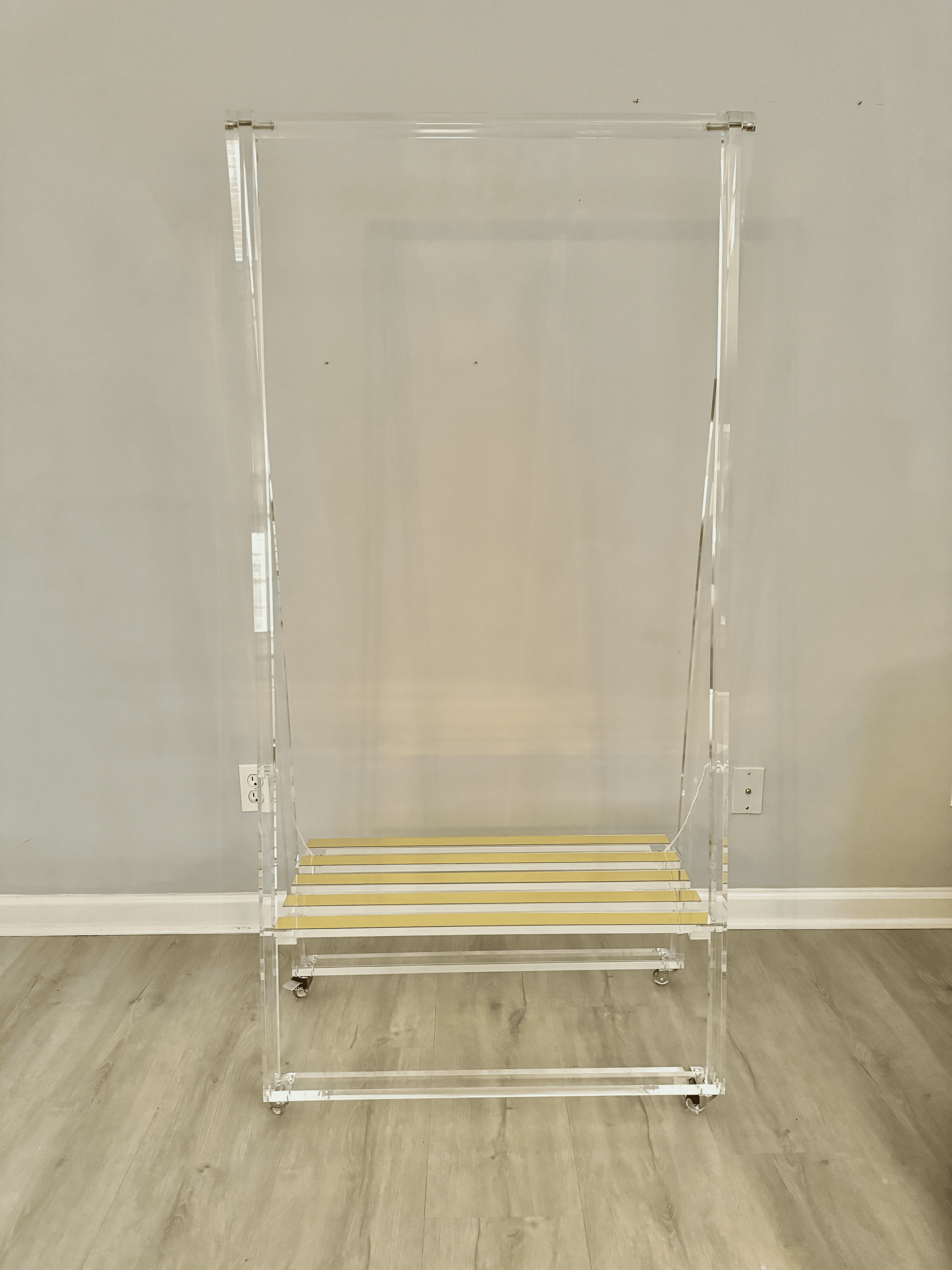Clear acrylic display case on a wooden floor against a beige wall.