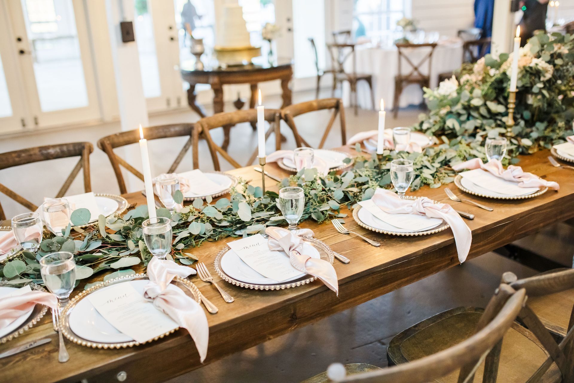 Elegant banquet table with white floral centerpieces, gold accents, and place settings in a bright room