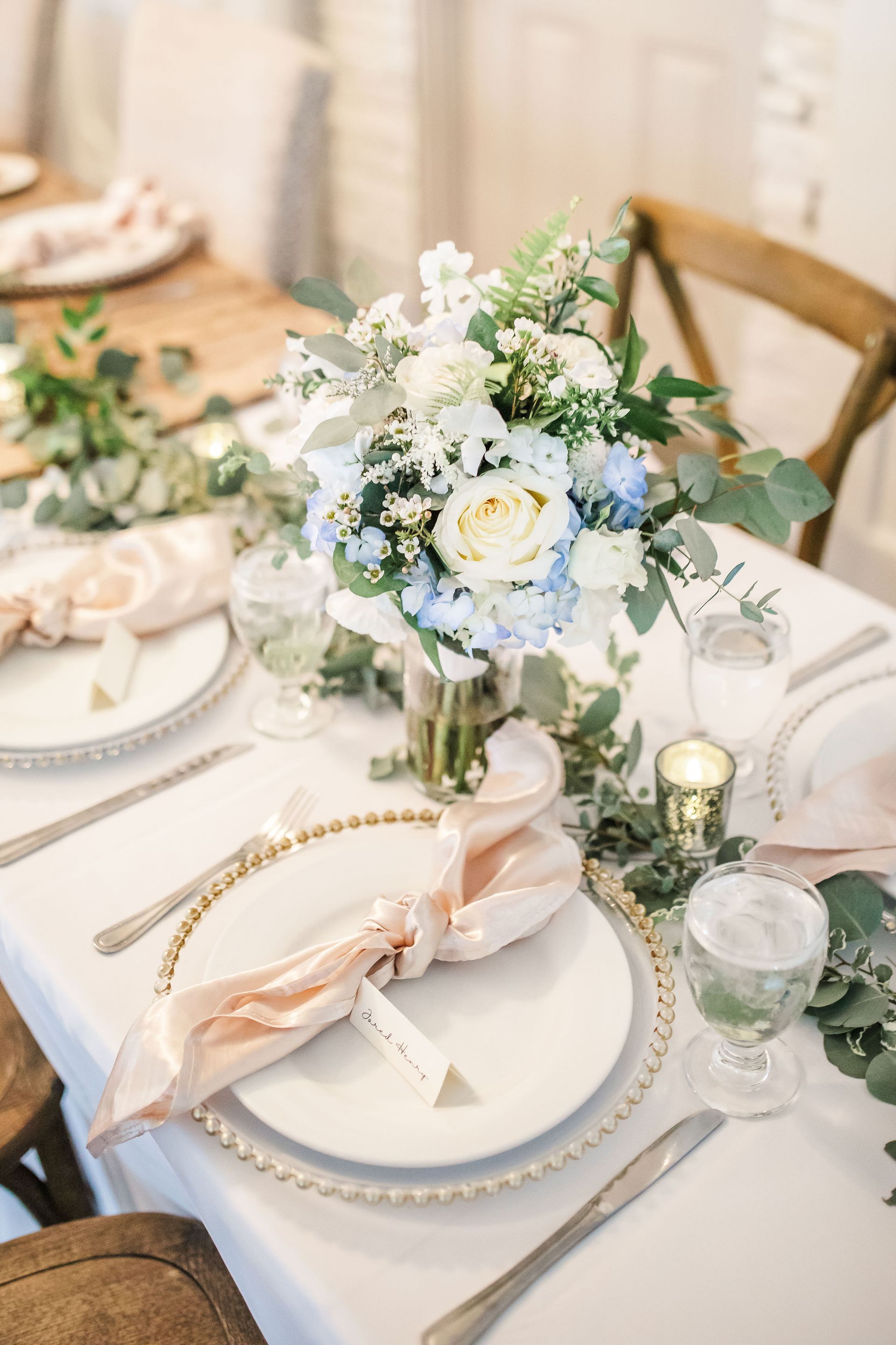 Elegant white-and-green floral centerpiece set on a formal dining table with gold-accented place settings