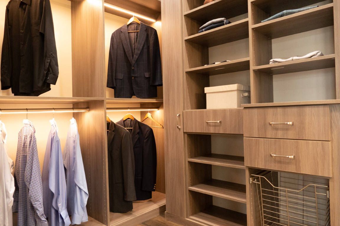 Walk-in closet with shelves and hanging clothes; wood finish.