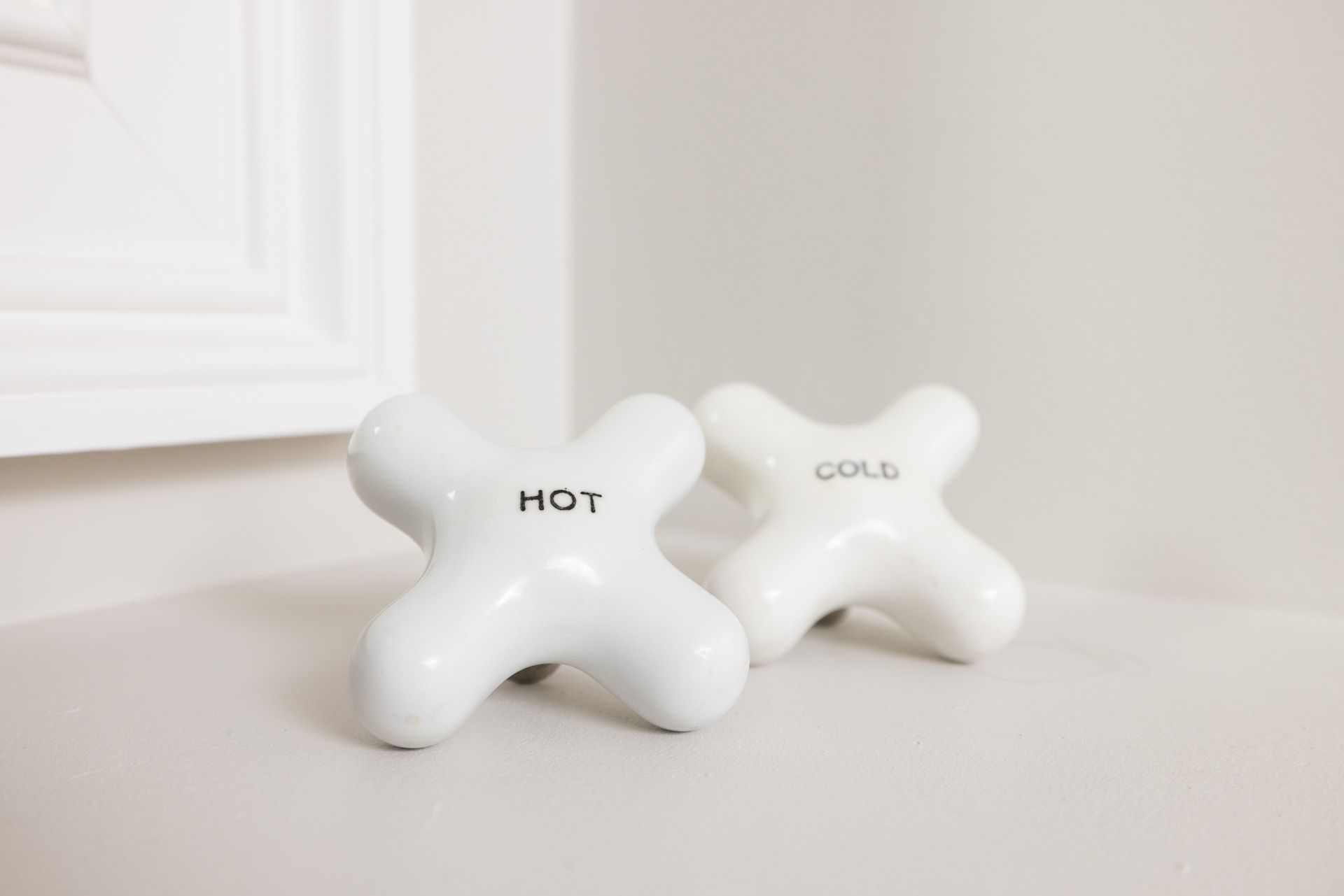 White ceramic faucet handles labeled
