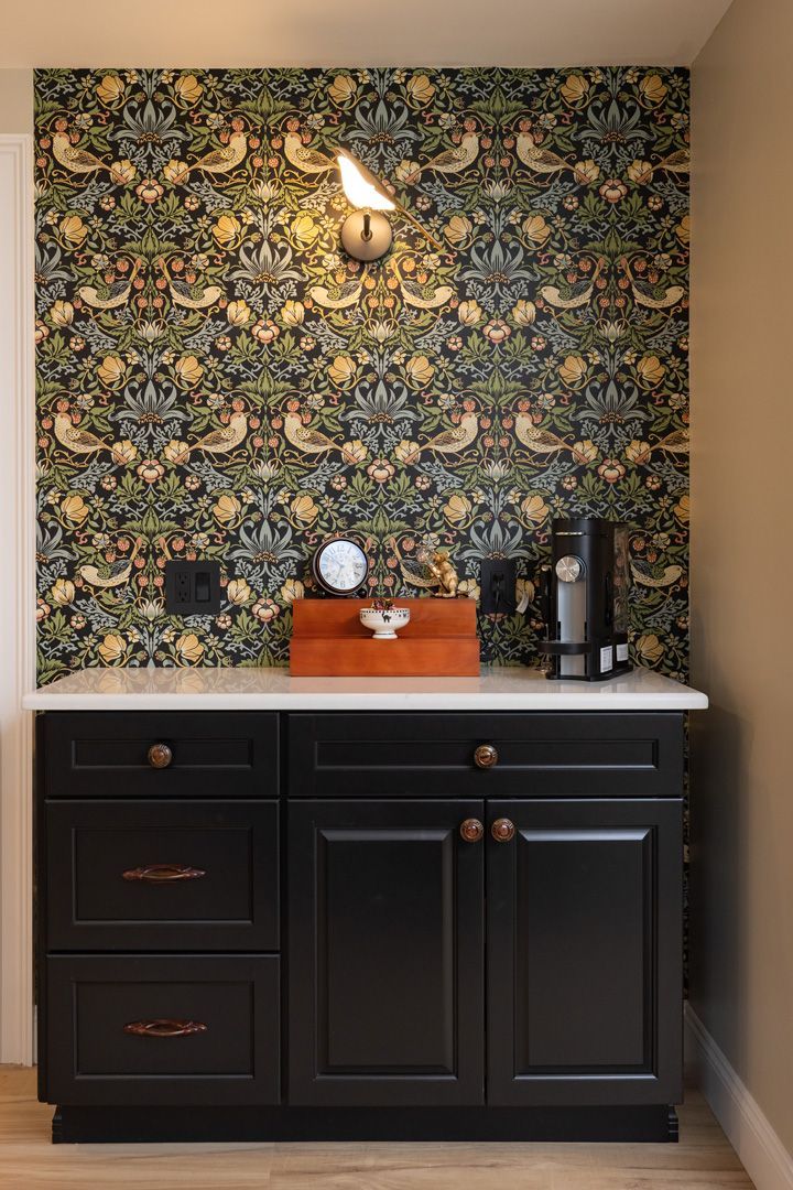 Black cabinet with a white countertop and floral wallpaper backdrop.