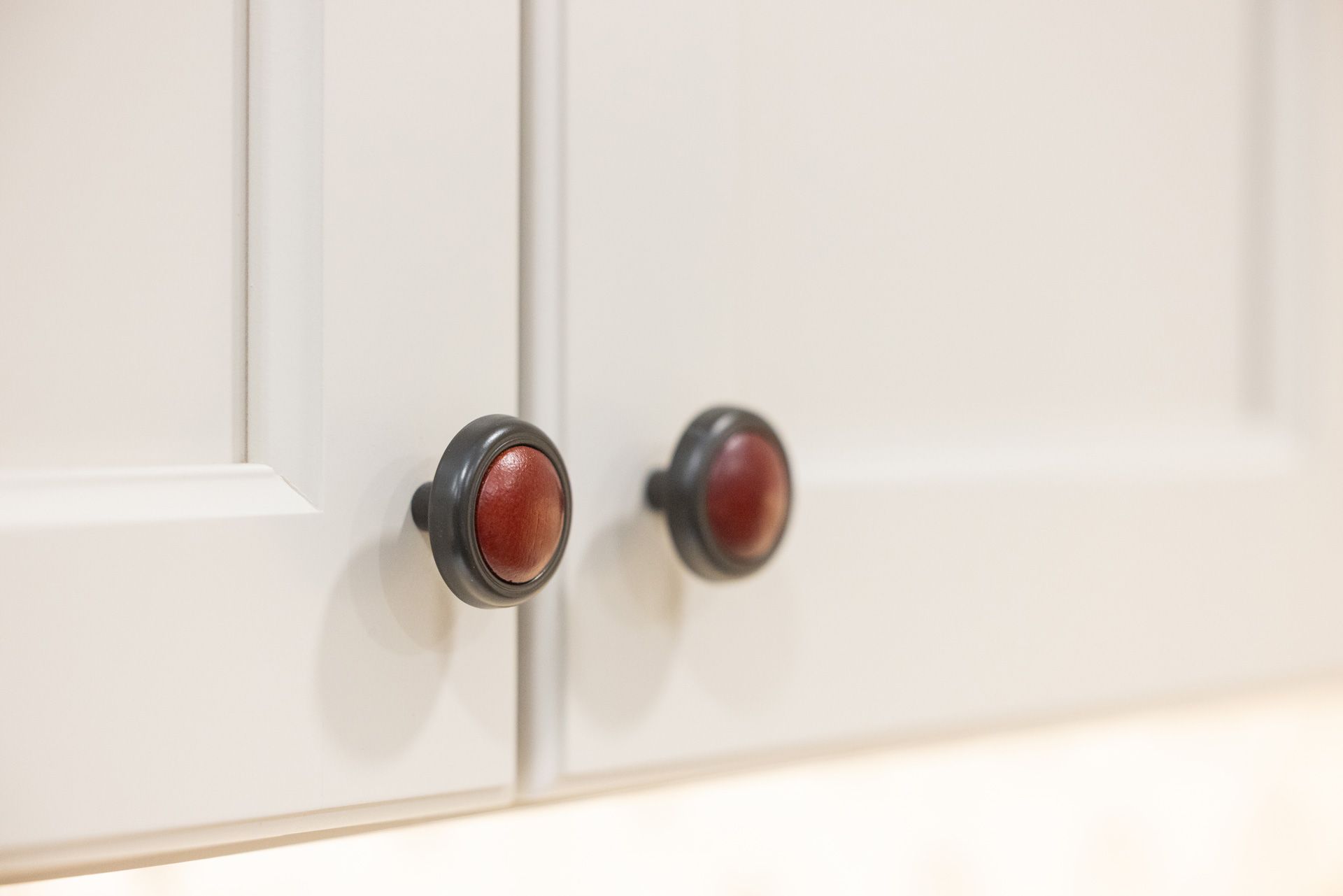 White cabinet doors with red-centered, dark-rimmed knobs.
