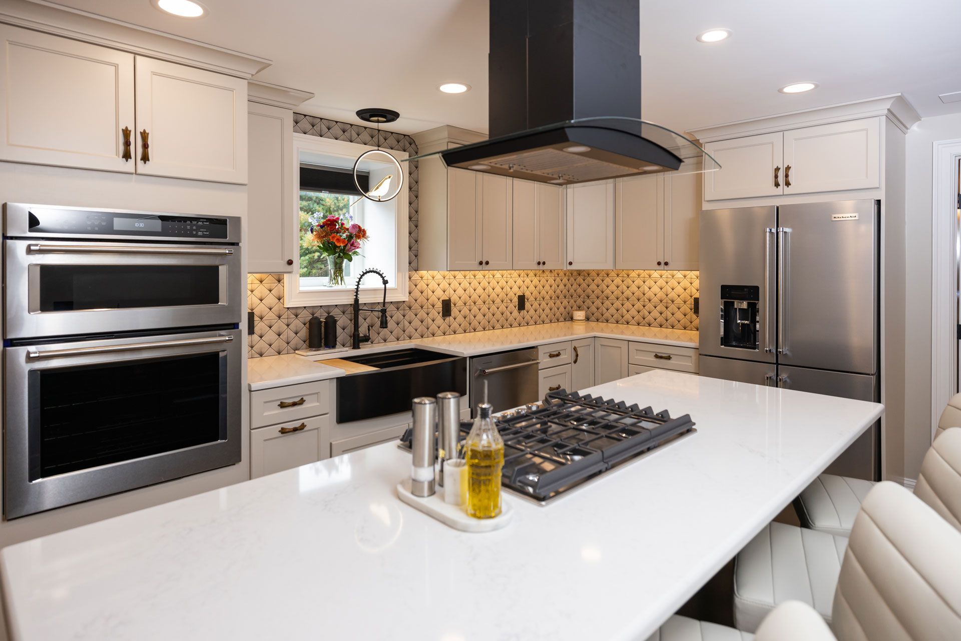 Modern kitchen with white cabinets, stainless steel appliances, and a central island with a stovetop.