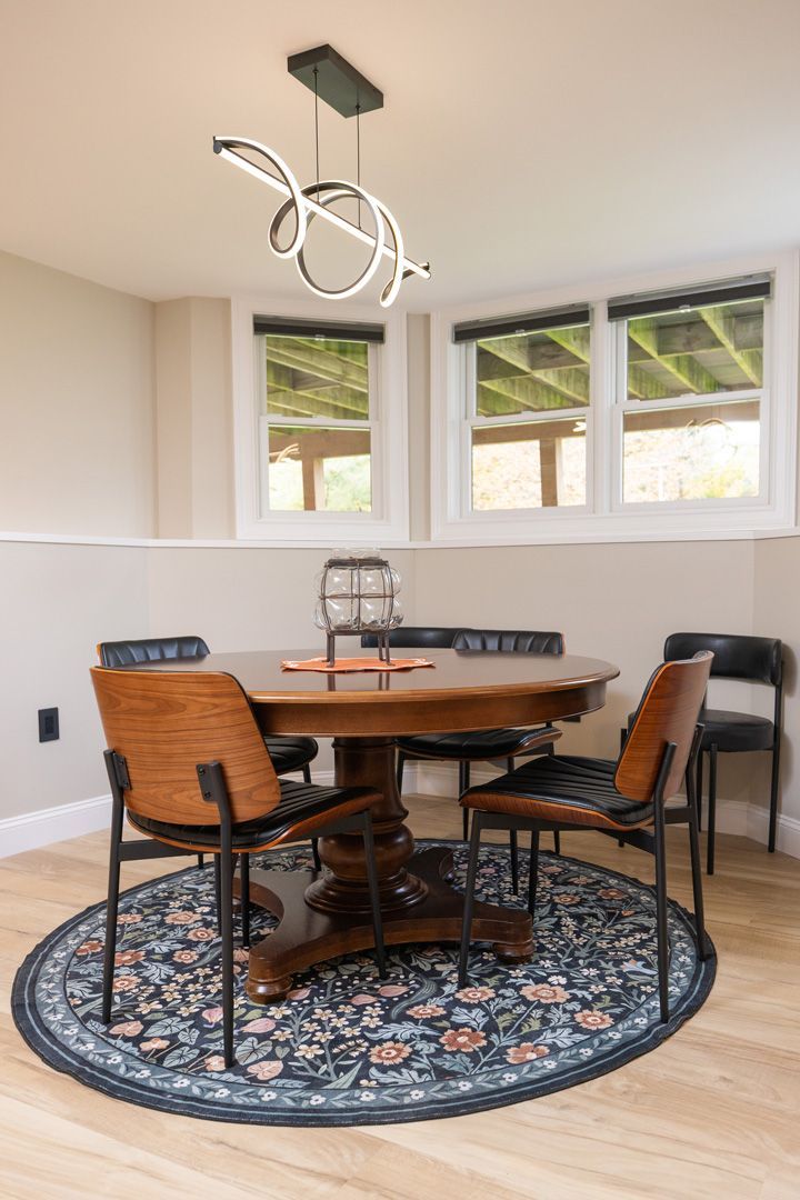 Dining nook with round table, four chairs, and a decorative rug. Light fixture overhead.