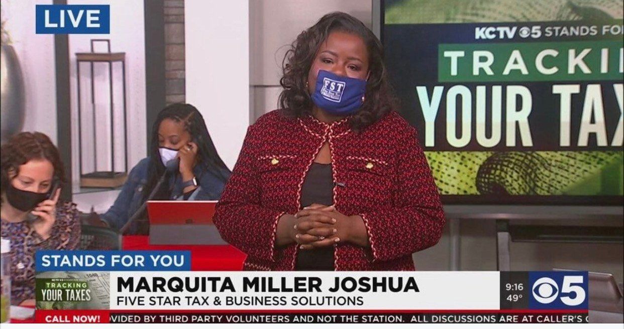 A woman wearing a mask is standing in front of a sign that says track your tax.