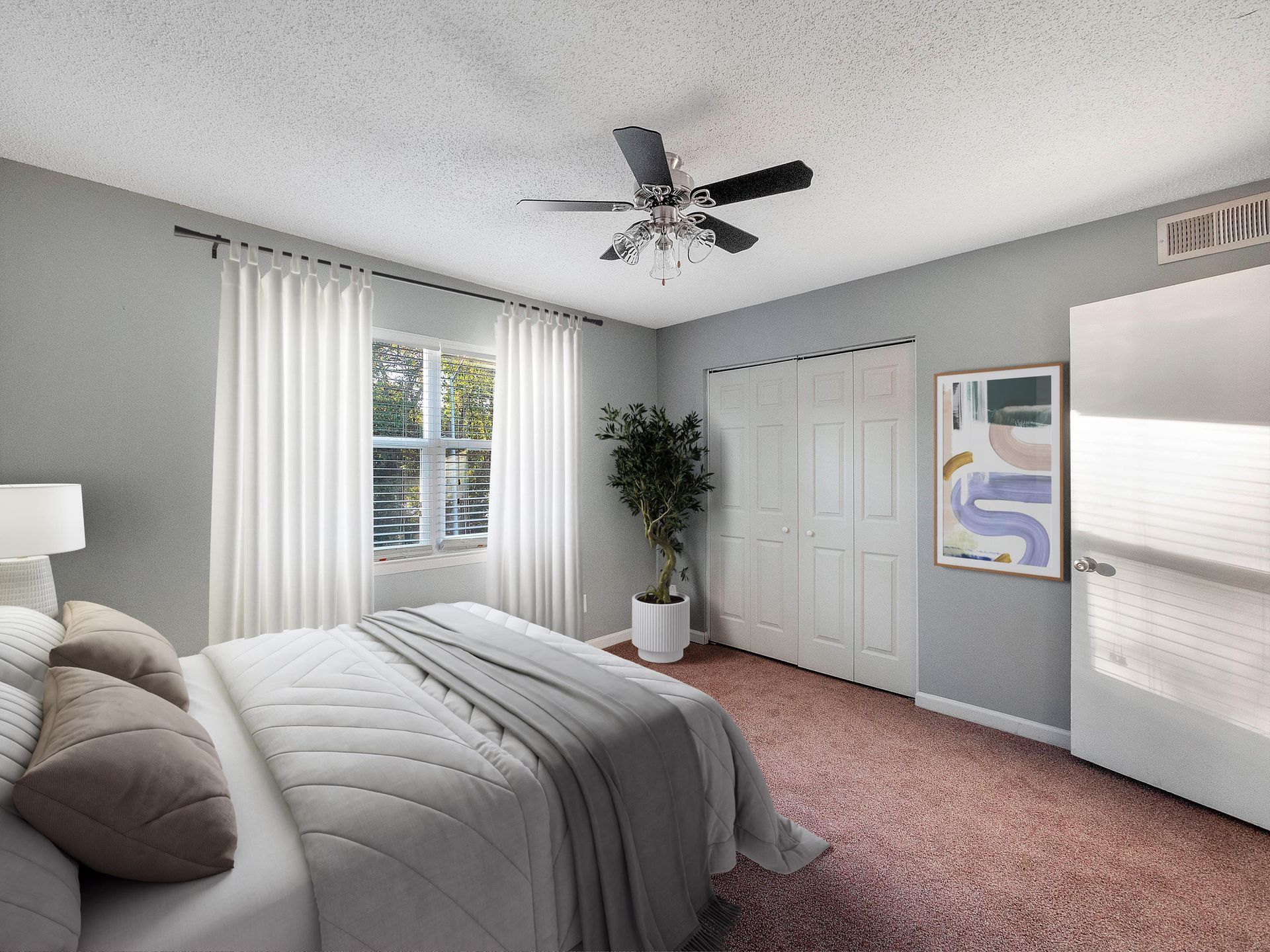 Bedroom with a bed, a window with white curtains, a potted plant, a ceiling fan, and grey walls with carpeted flooring.