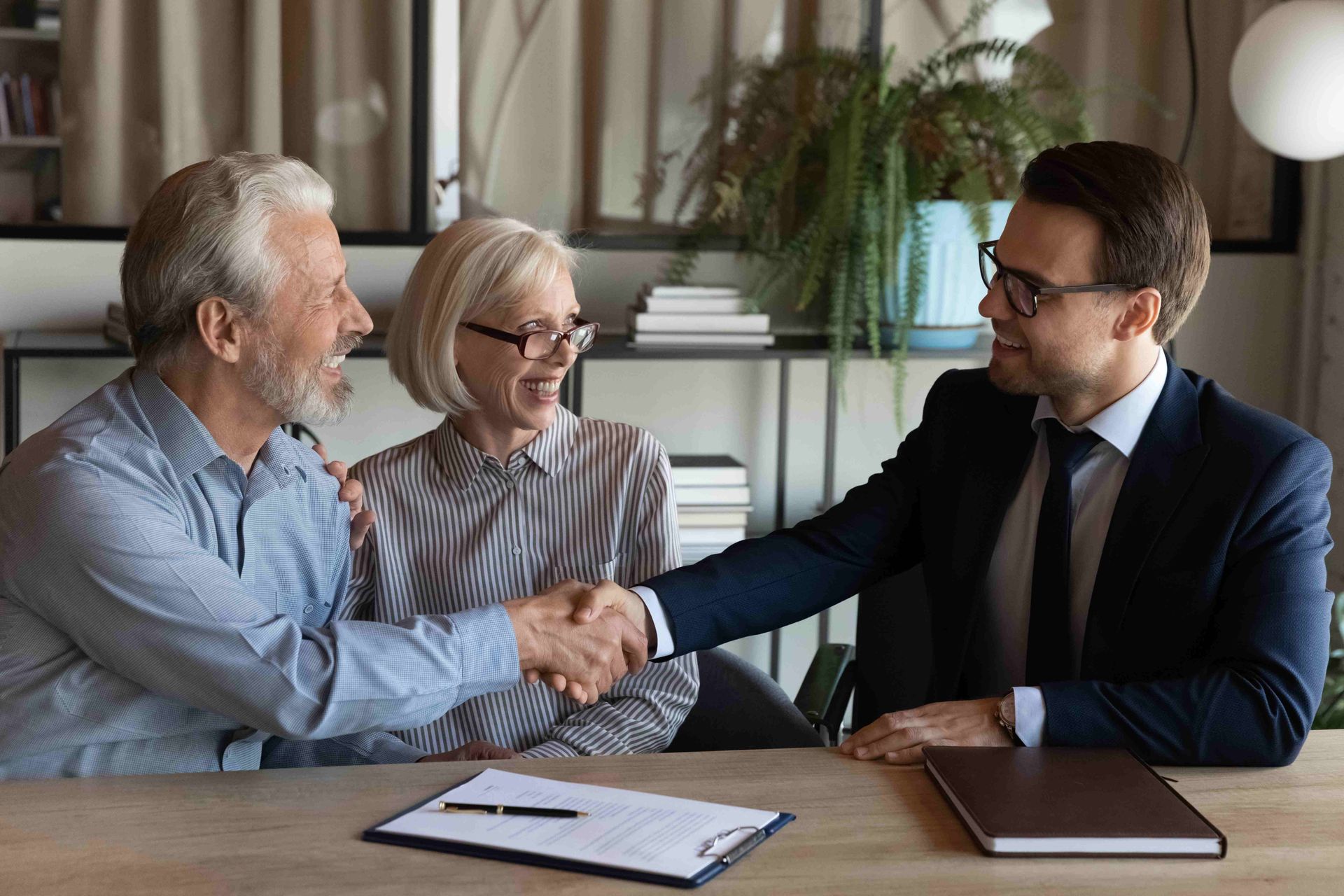 a man in a suit shakes hands with an older couple
