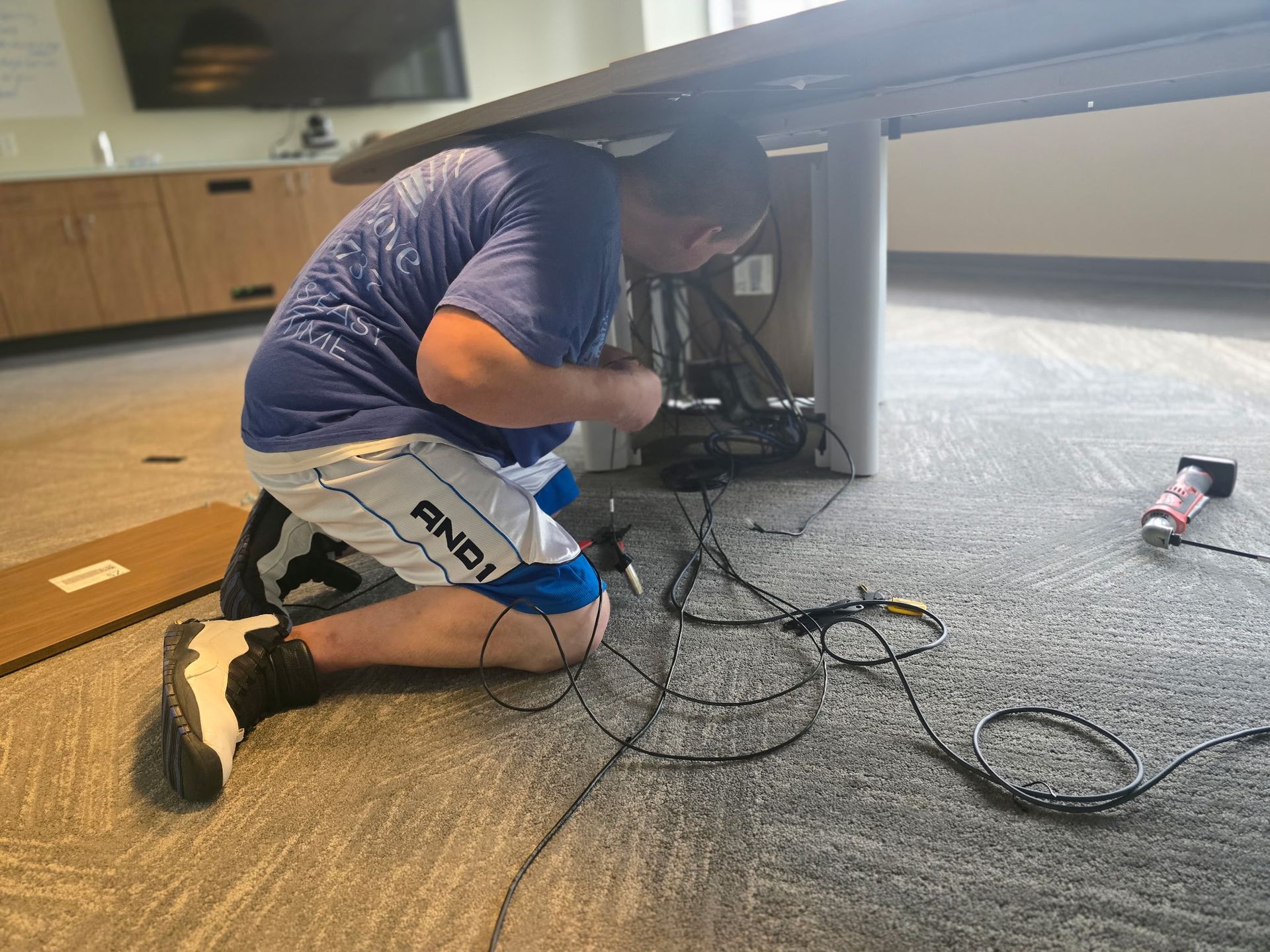 JHUM team member expertly separating wires for professional conference table disassembly.