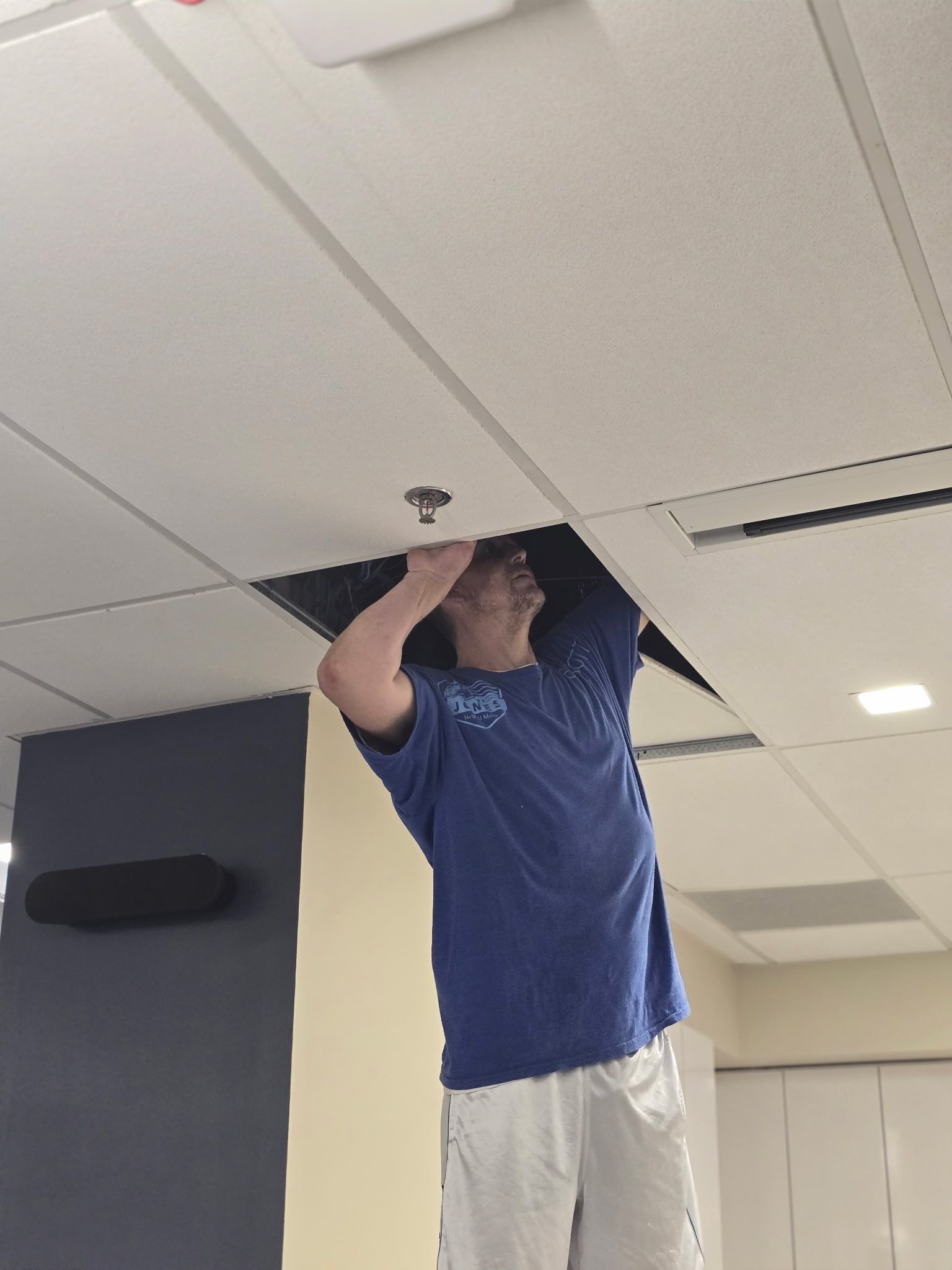 JHUM team member going above and beyond assisting office moving client with an issue in their panel ceiling. 