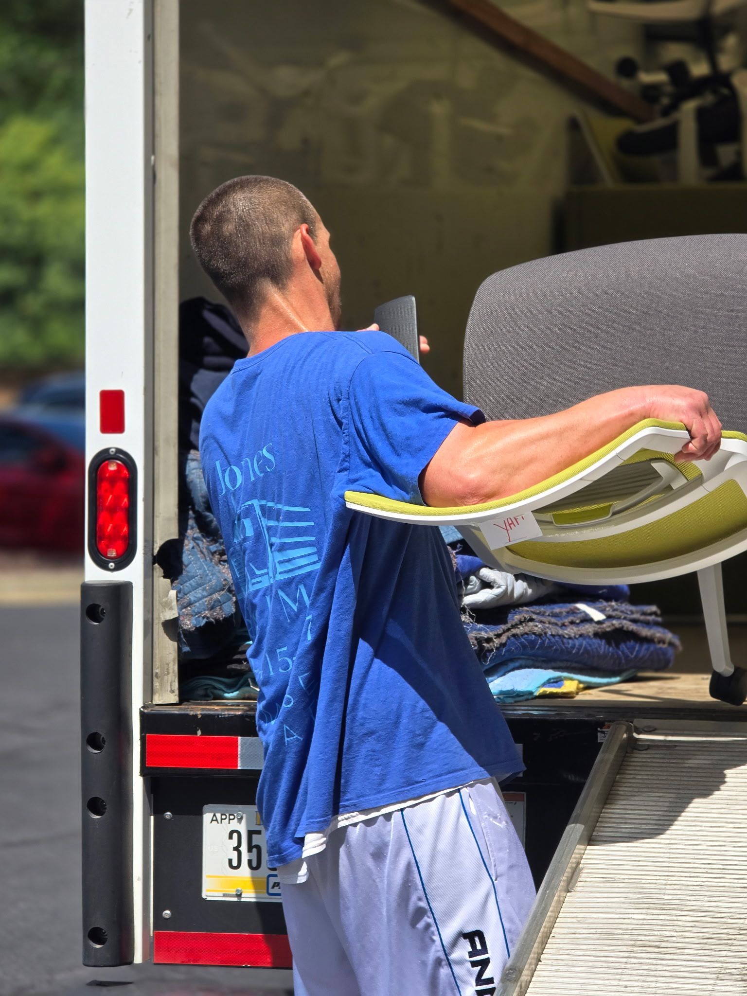A JHUM team member expertly loading office equipment into a professional moving vehicle.
