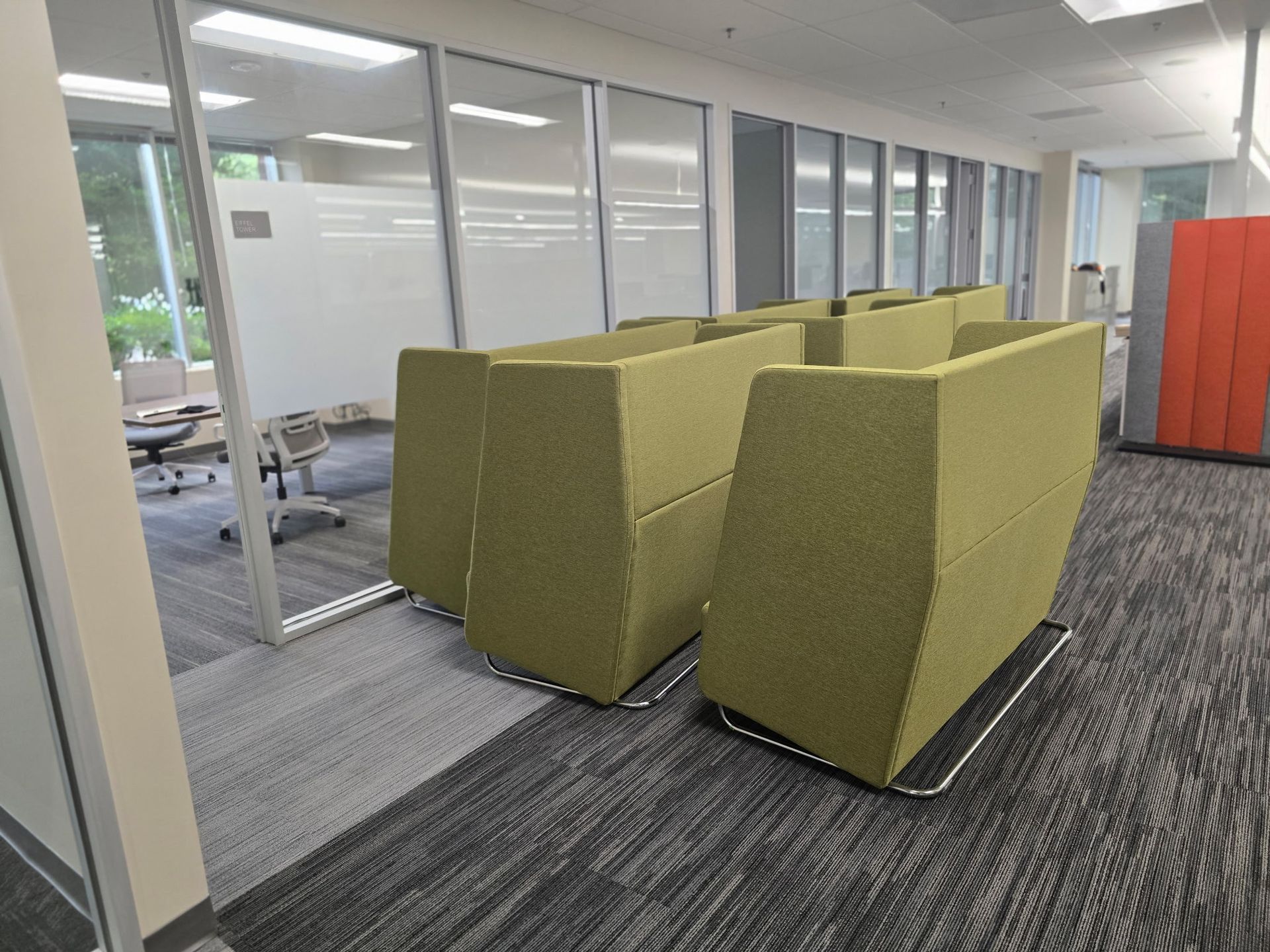 Office space with modular green seating, glass walls, and a patterned carpet professionally being prepared for transport.