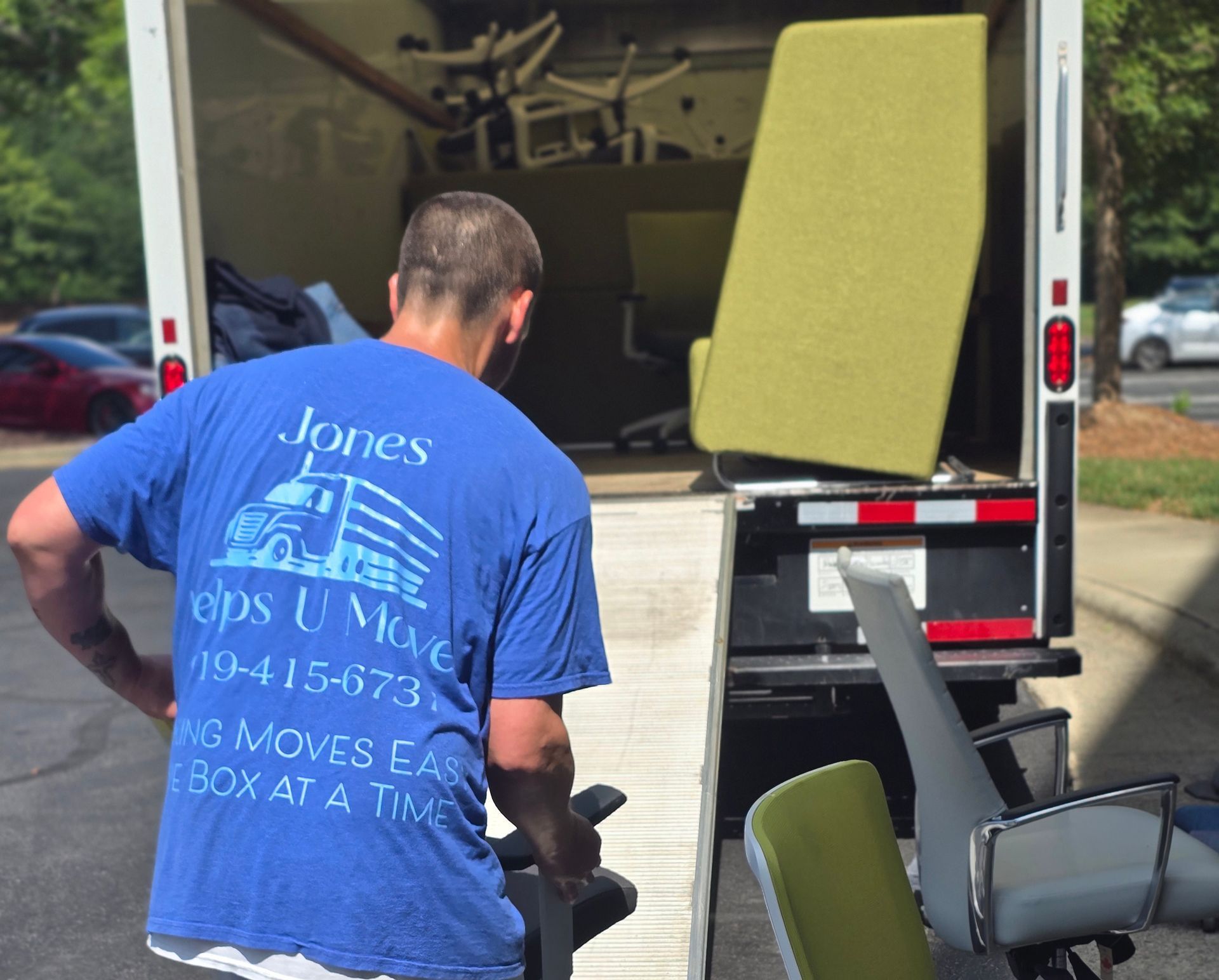 A full-time employee of Jones Helps U Move loading heavy office equipment into a commercial moving truck.
