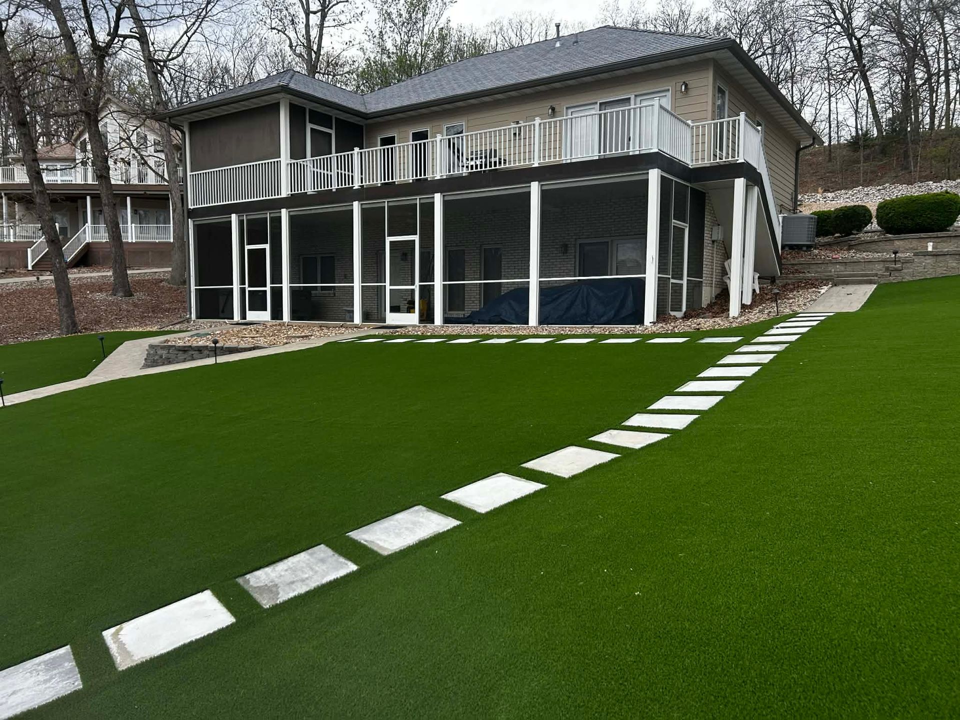Modern house with glass porch and a bright green lawn bordered by stepping stones