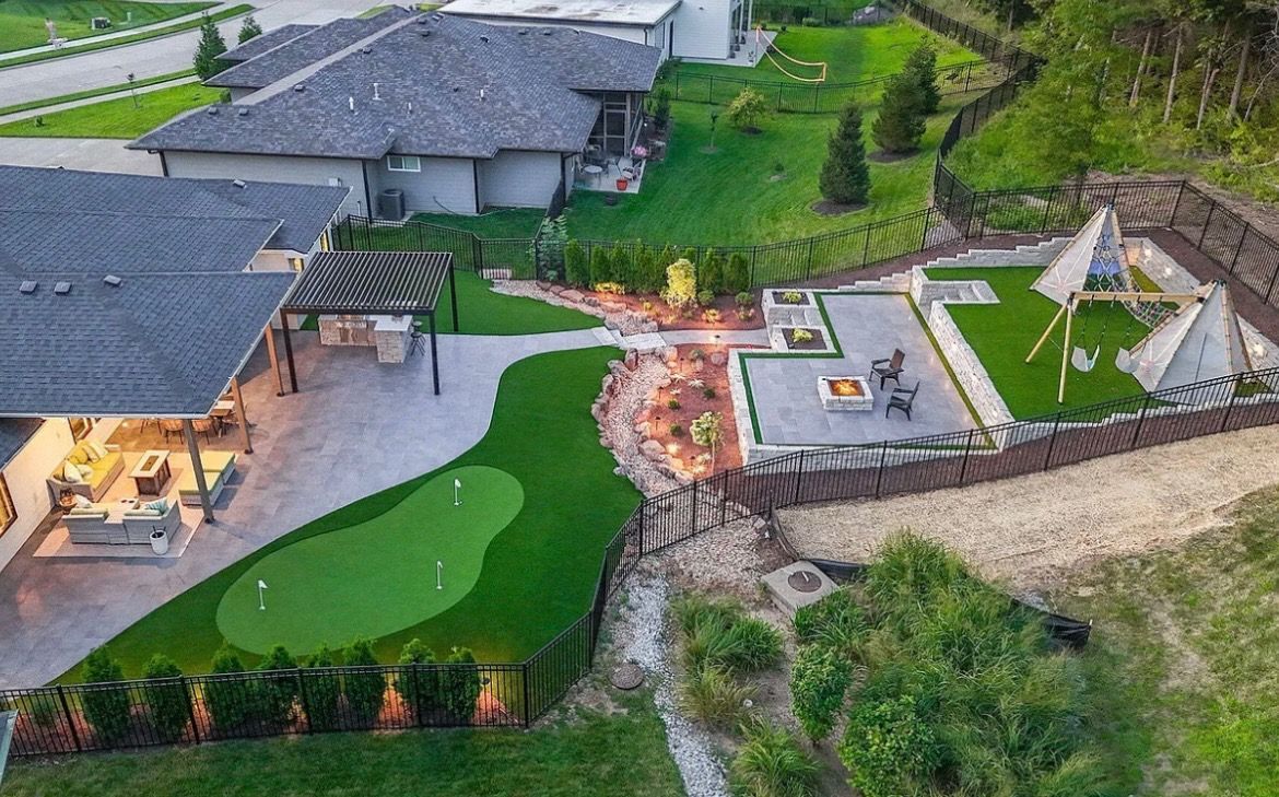 Aerial view of a modern house with a green lawn, patio, and landscaped backyard.