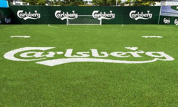 Carlsberg soccer field with white logo on green grass and sponsor boards in the background