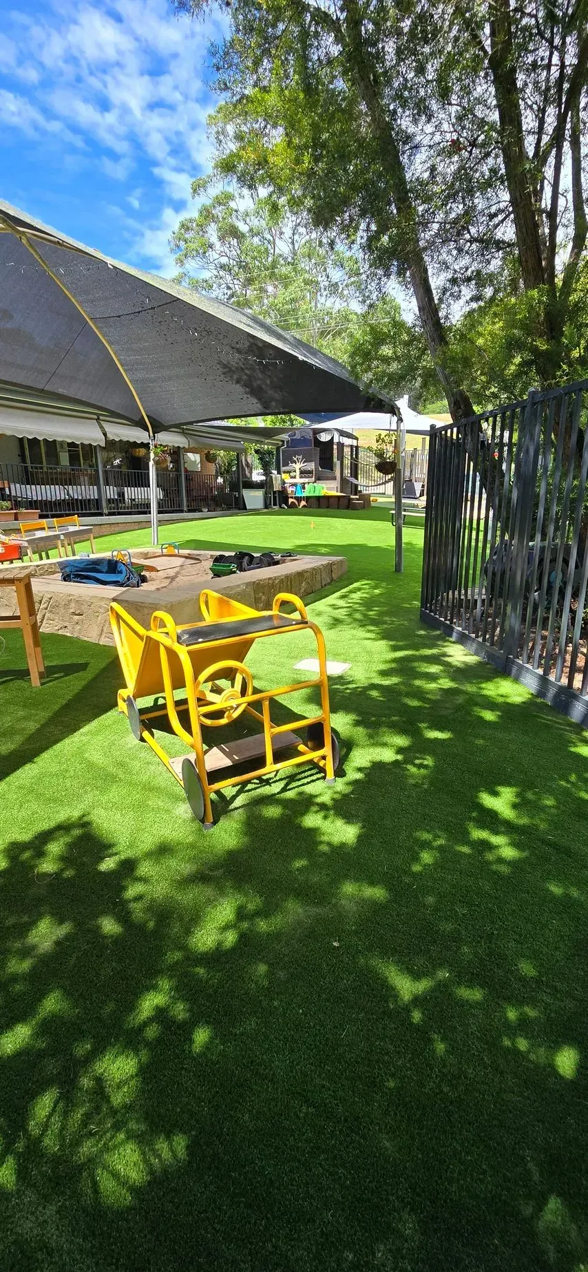 Yellow outdoor chairs on a sunny lawn beside a building and trees