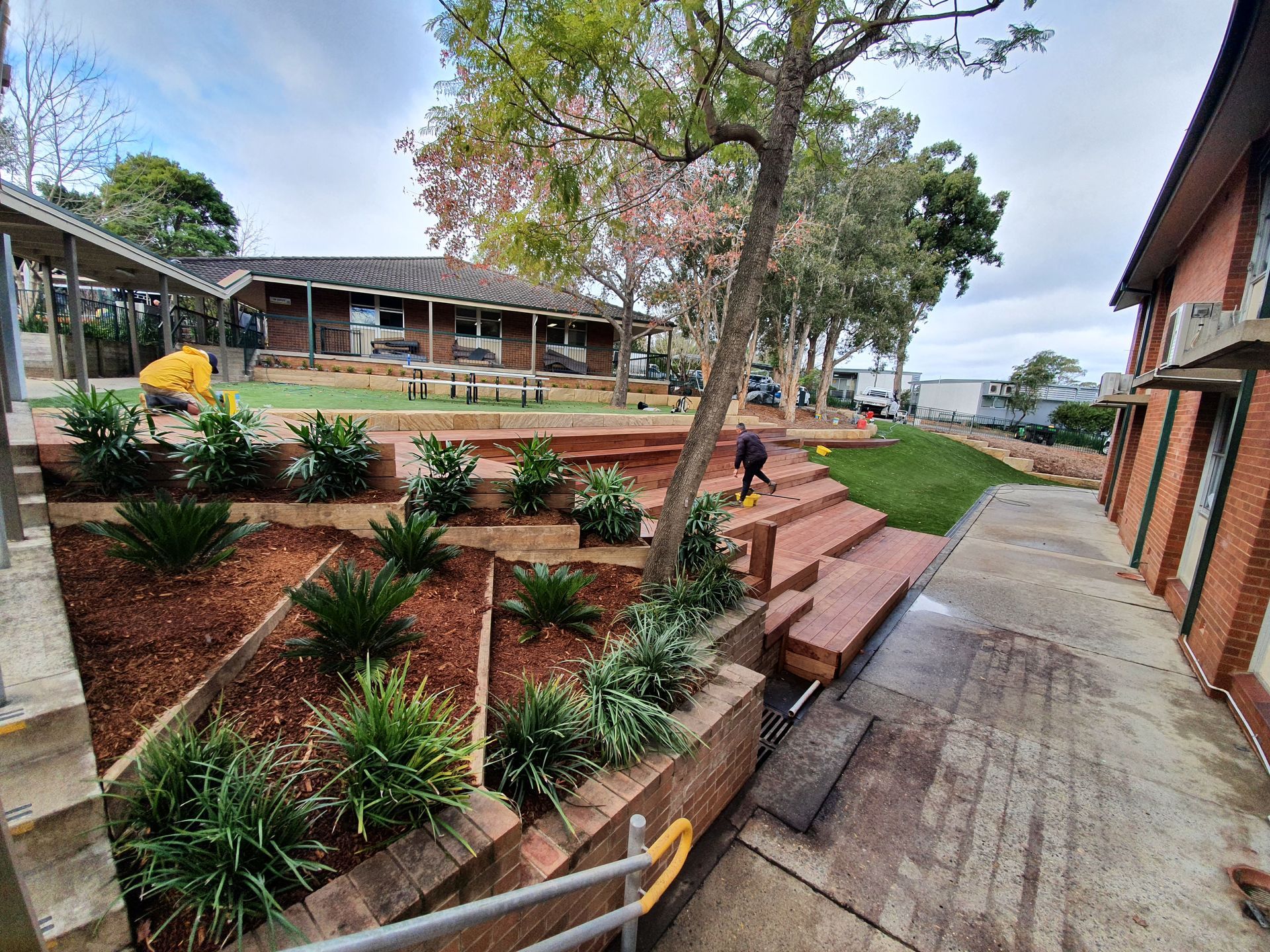 Landscaped courtyard with brick steps, potted plants, and a concrete walkway beside a building