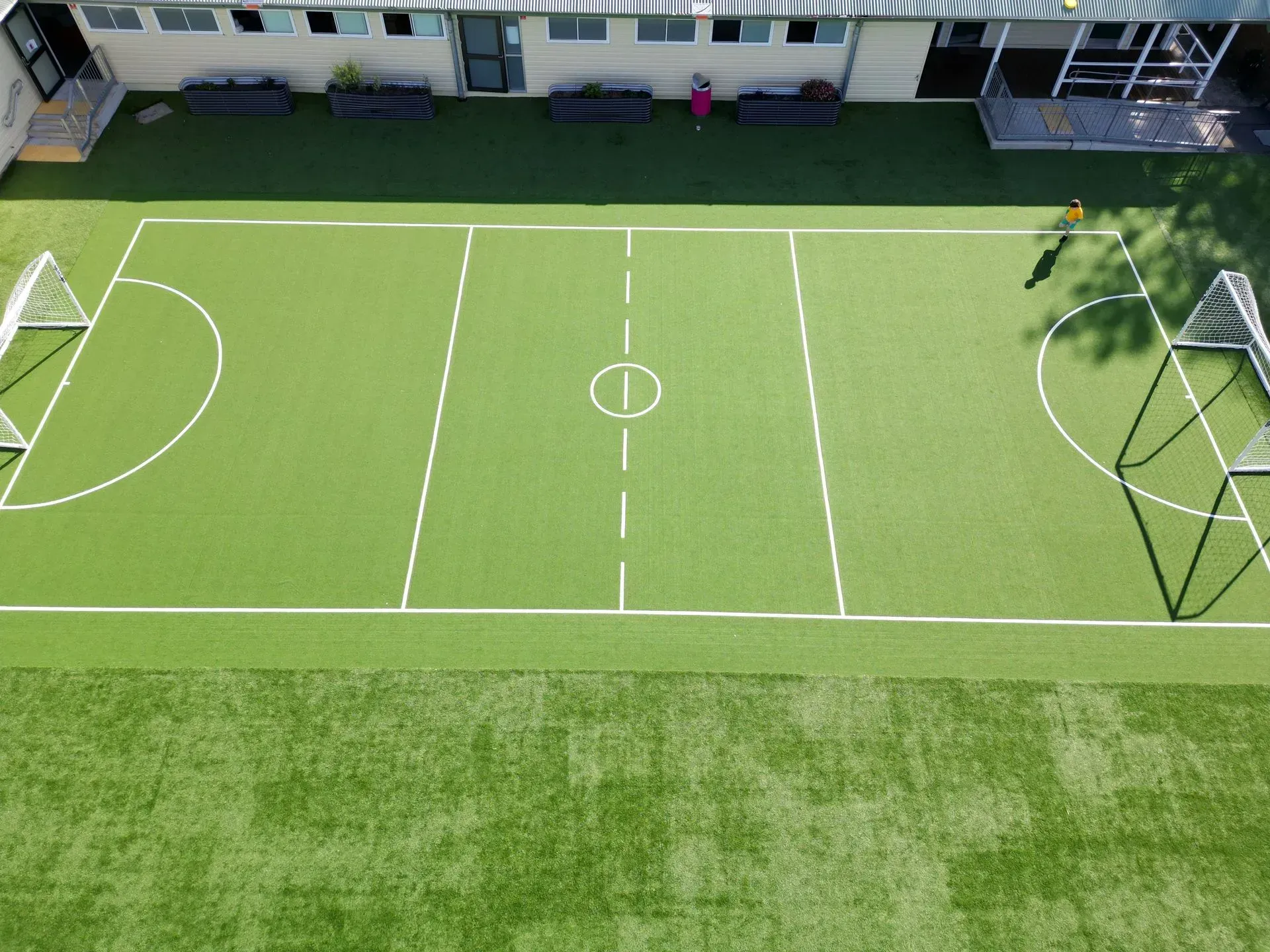 Empty green soccer field with white lines and goals, viewed from above