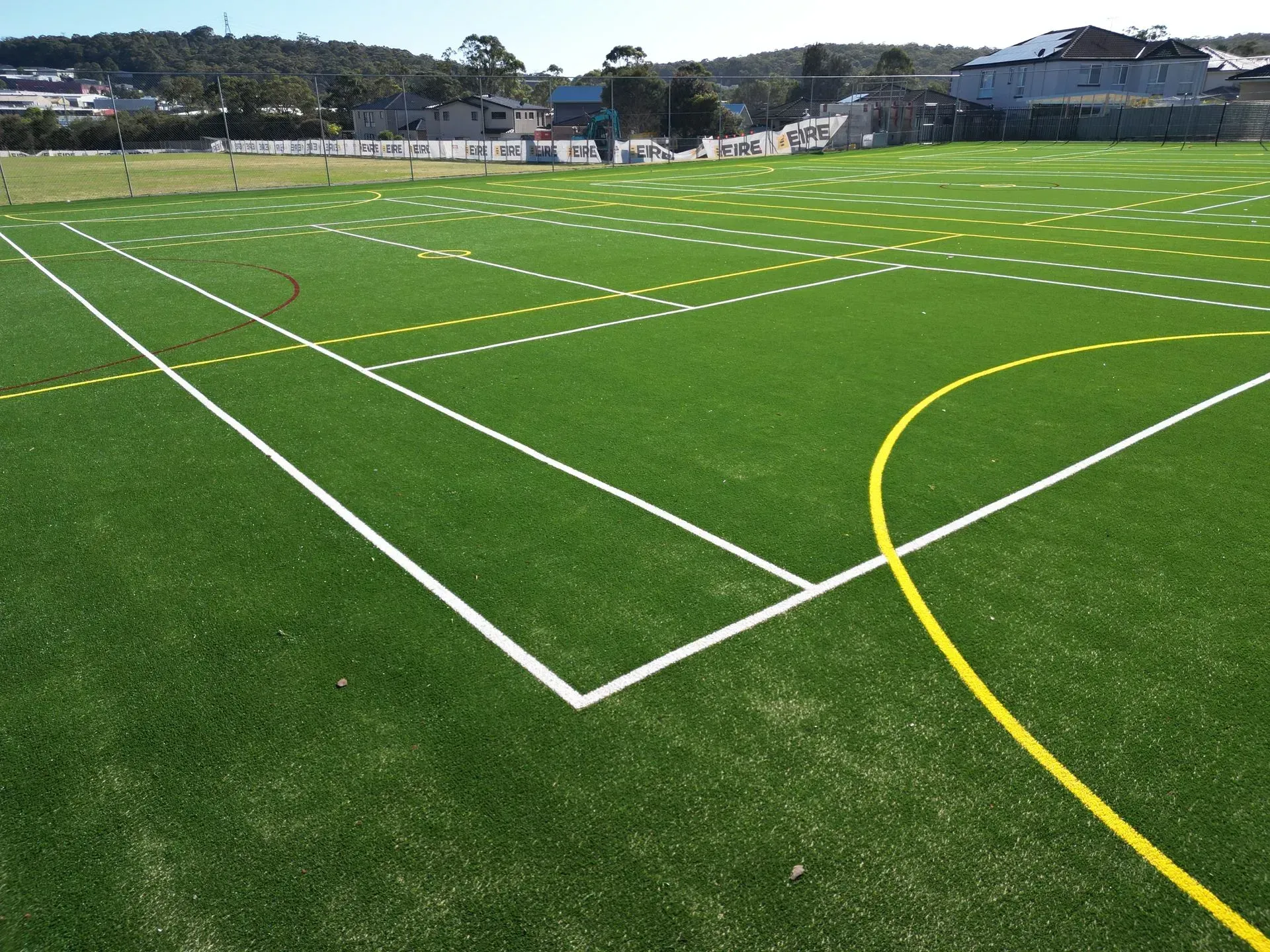 Green sports field with white and yellow lines under a clear sky
