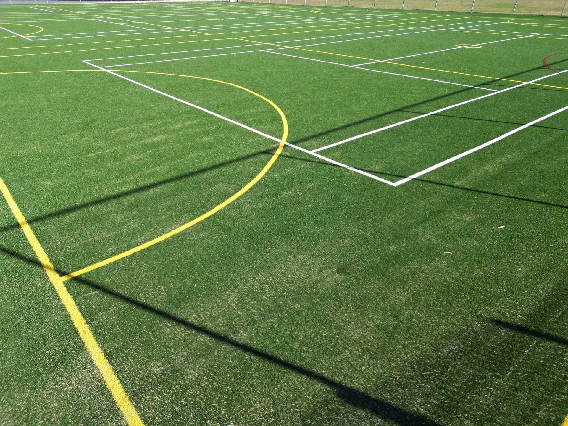 Green sports field with white and yellow boundary lines on artificial turf