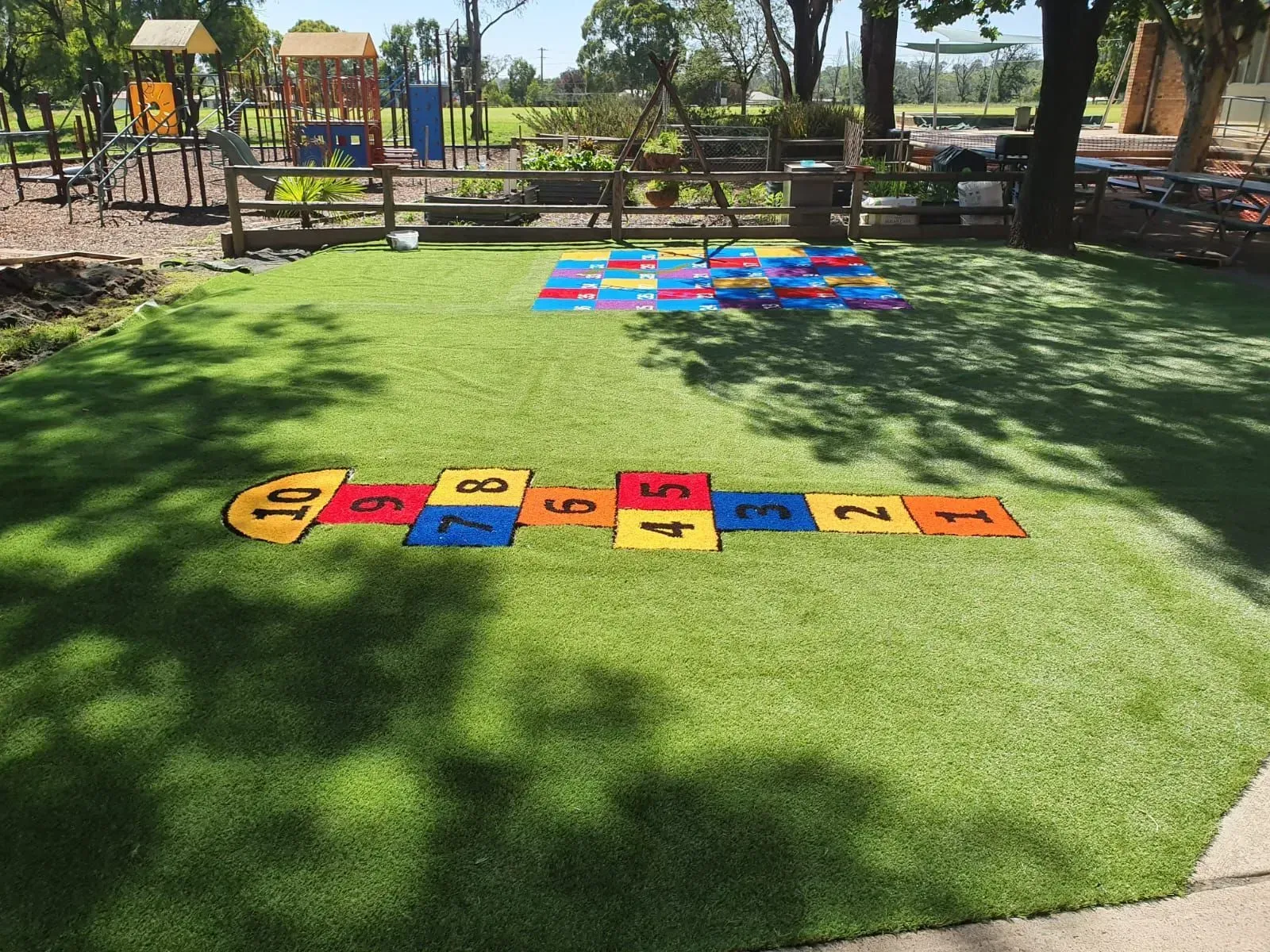 Colorful hopscotch mats on grass in a sunny park playground
