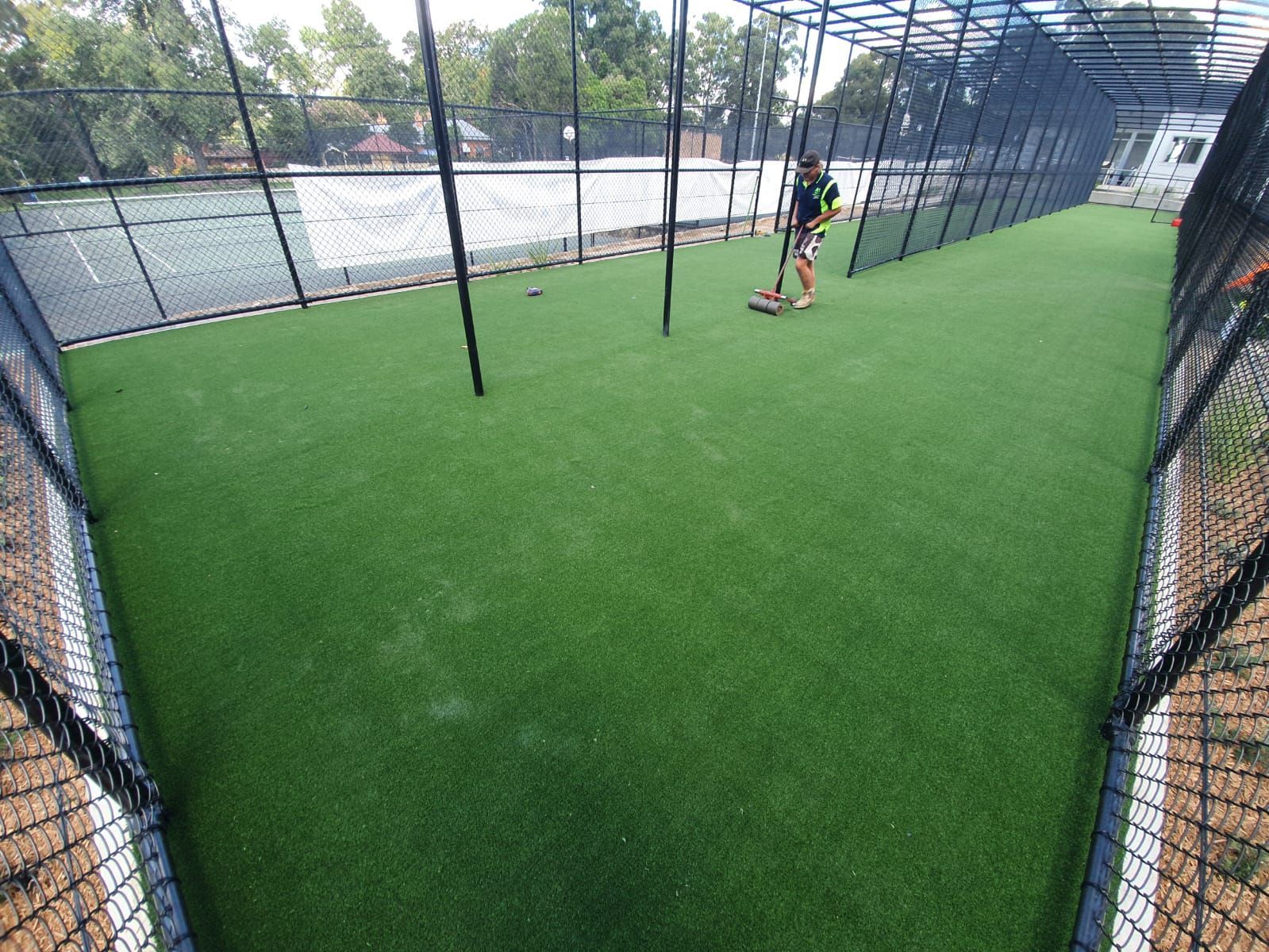 Indoor turf field behind chain-link fence, with a person using a soccer ball near the far end.