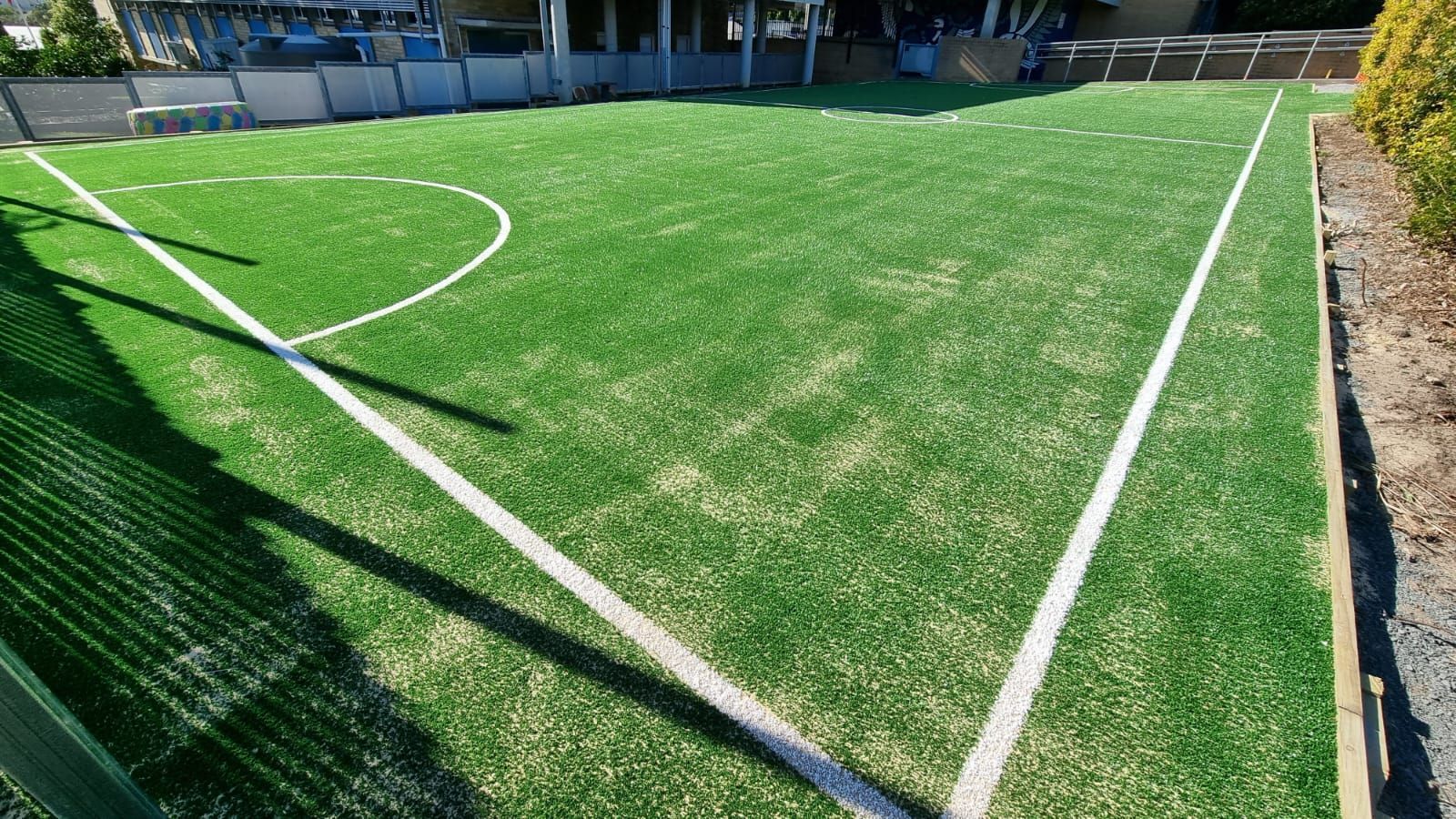 Artificial turf soccer field corner with white boundary lines and a goal area.