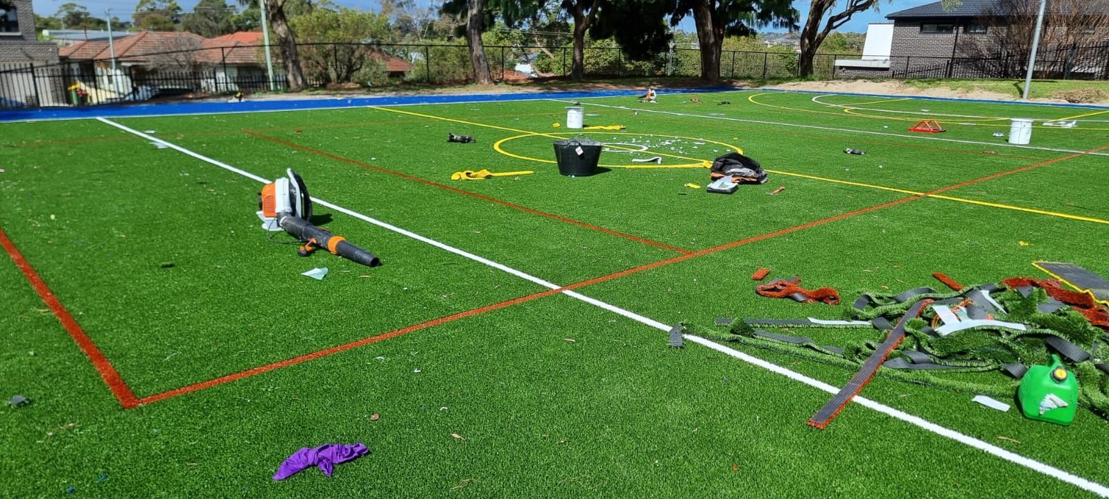 Sports field with cones, markers, and scattered equipment on green turf under bright sunlight