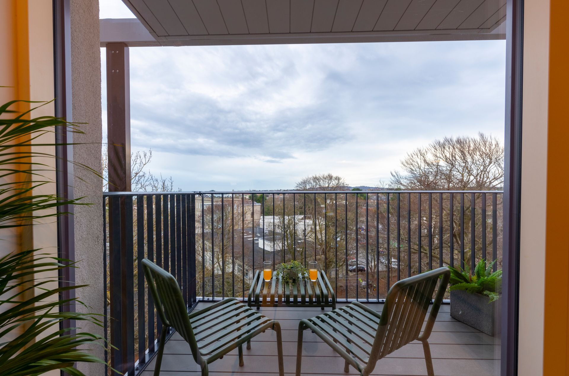 A balcony with two chairs and a table with a view of the city.