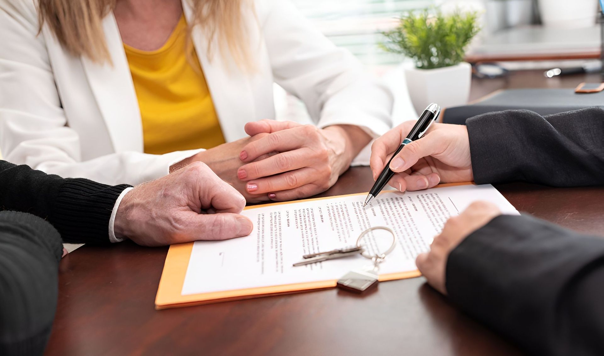 A Man And A Woman Are Sitting At A Table Signing A Document — Grant Finance Solutions In Gold Coast, QLD
