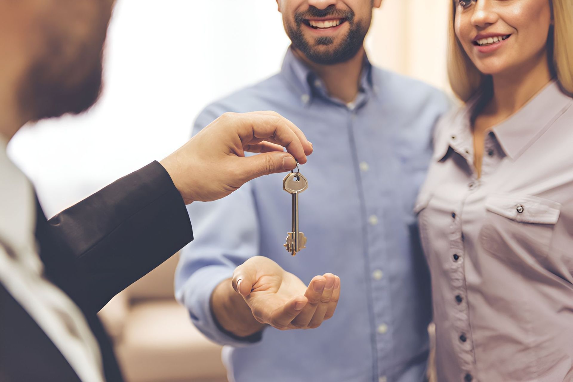 A Man Is Giving A Key To A Woman And A Man — Grant Finance Solutions In Toowoomba, QLD