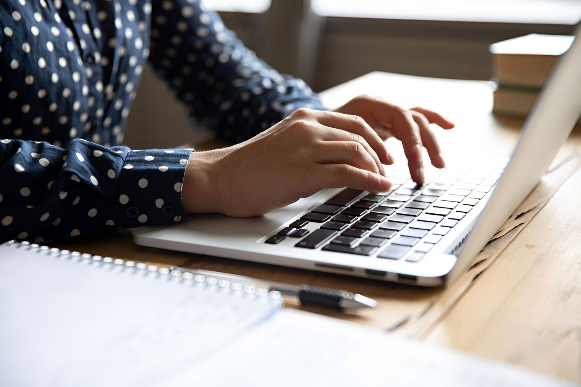 A Woman Is Typing On A Laptop Computer On A Wooden Desk — Grant Finance Solutions In Toowoomba, QLD