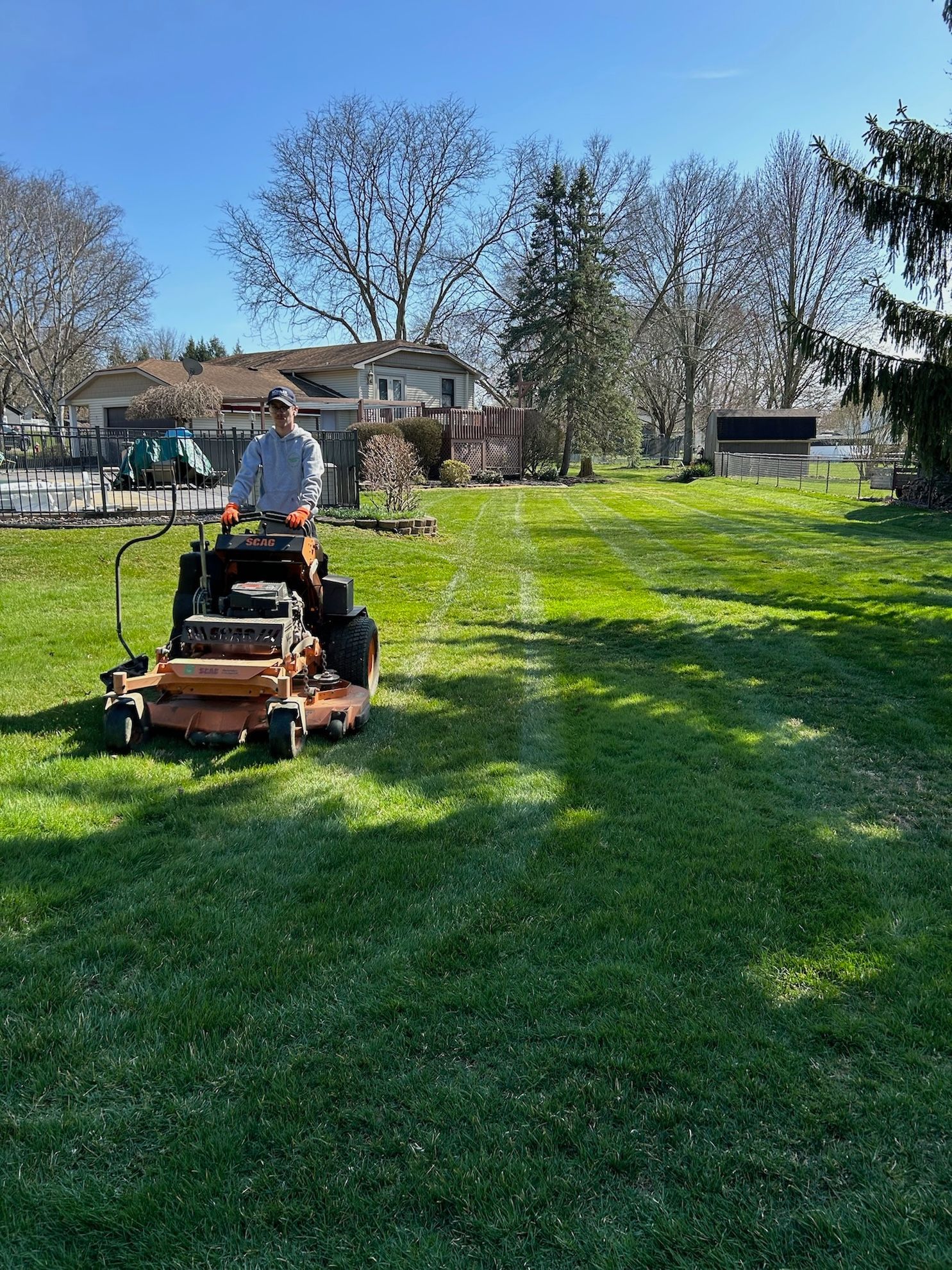 A man is riding a lawn mower on a lush green lawn.