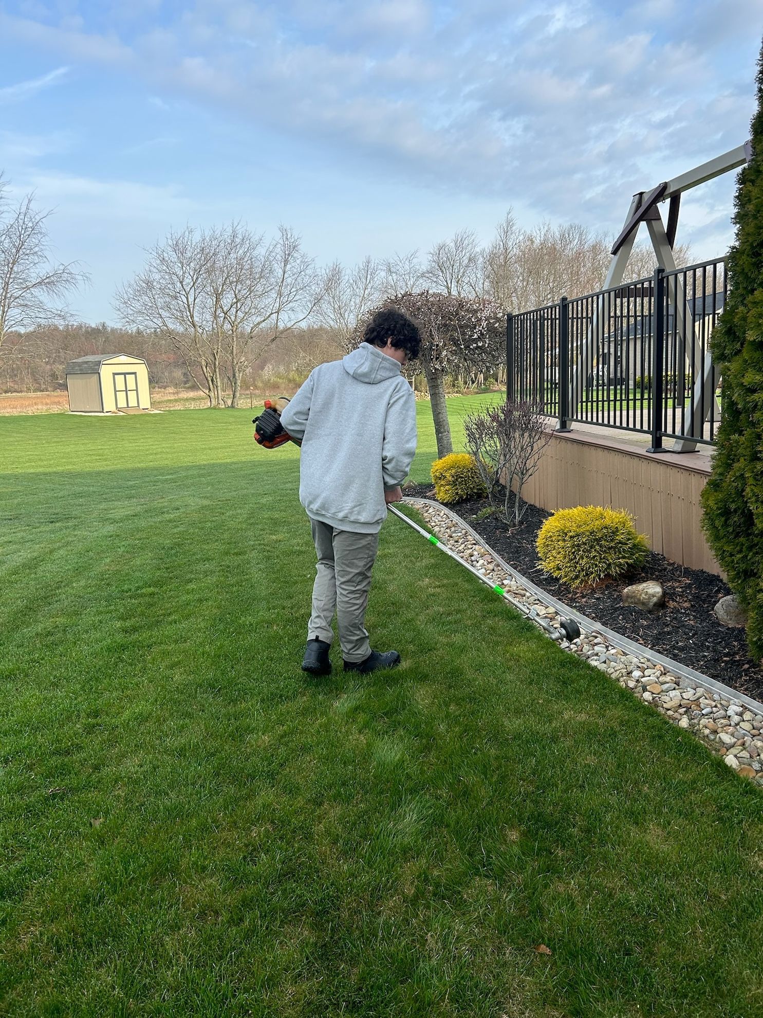 A man is using a lawn mower to cut the grass in a yard.