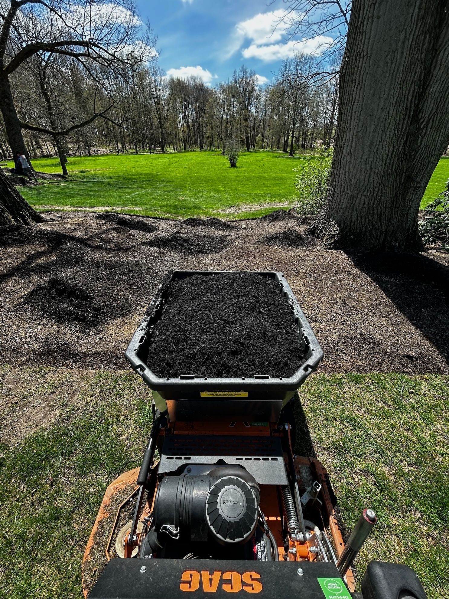 A lawn mower with a bucket of dirt on top of it.