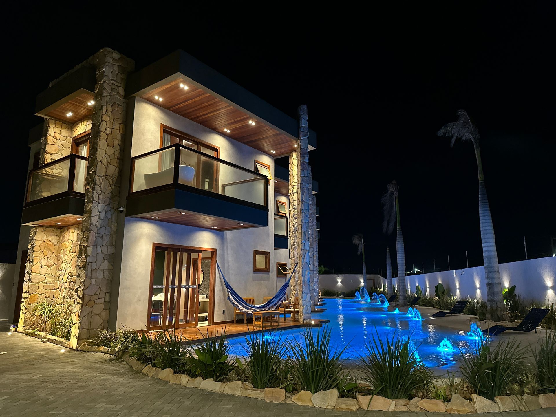 Uma casa com uma piscina na frente à noite.